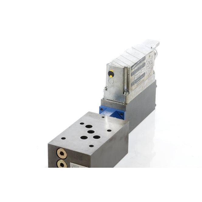 Metallisches Industrieventil oder mechanische Komponente mit gebohrtem Montageblock und angeflanschtem Stellantrieb, dargestellt vor weißem Hintergrund.