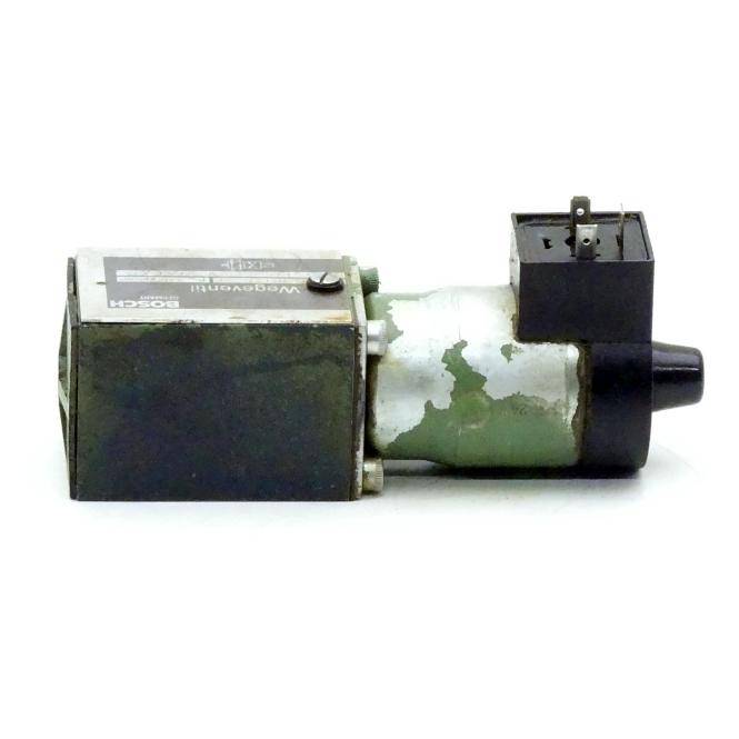 Ein kleiner verschlissener industrieller Elektromotor oder Aktor mit schwarzem Gehäuse und abblätternder grüner Farbe, dargestellt vor weißem Hintergrund.