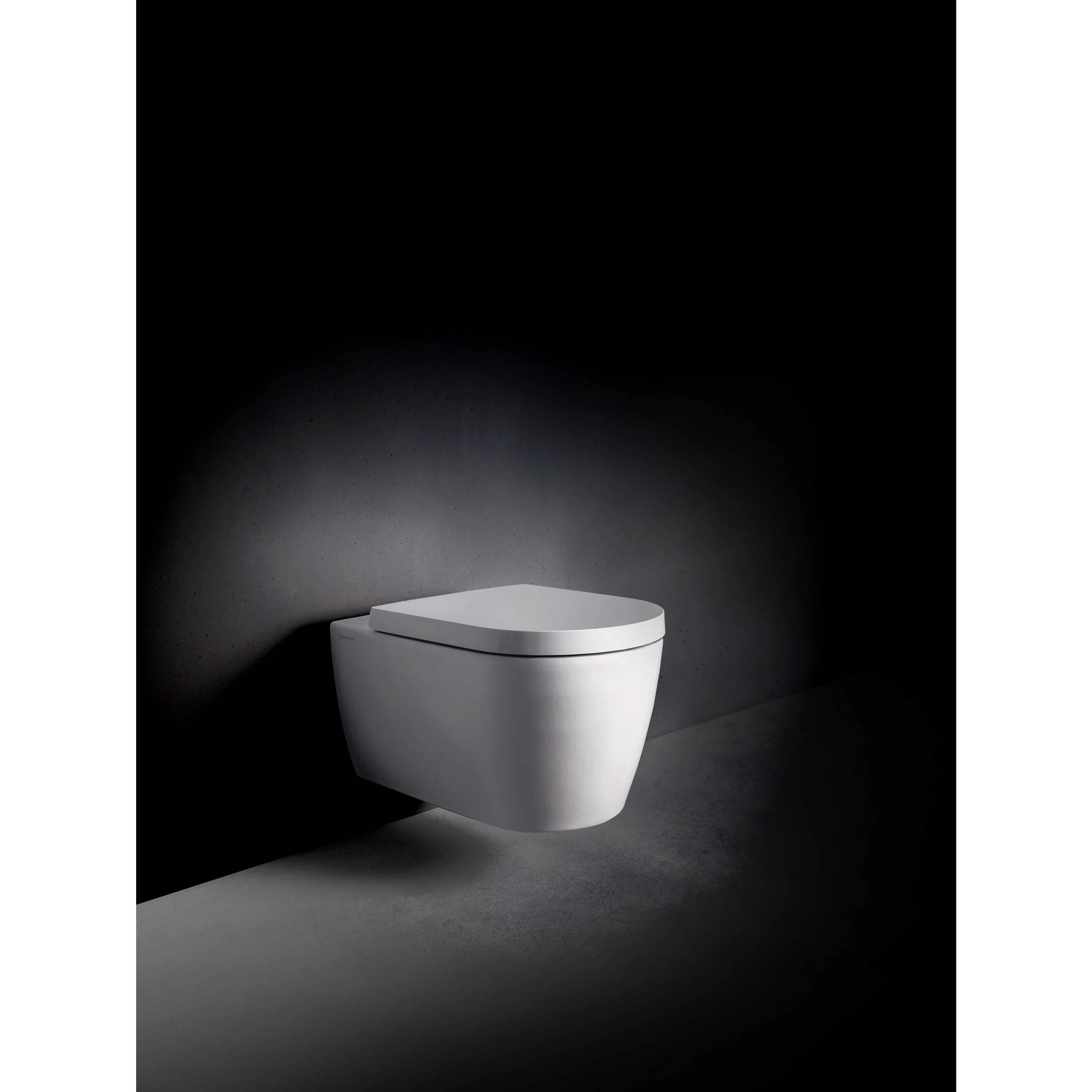 Modernes weiß wandmontiertes Toilettenbecken an einer dunklen minimalistischen Badezimmerwand und Boden