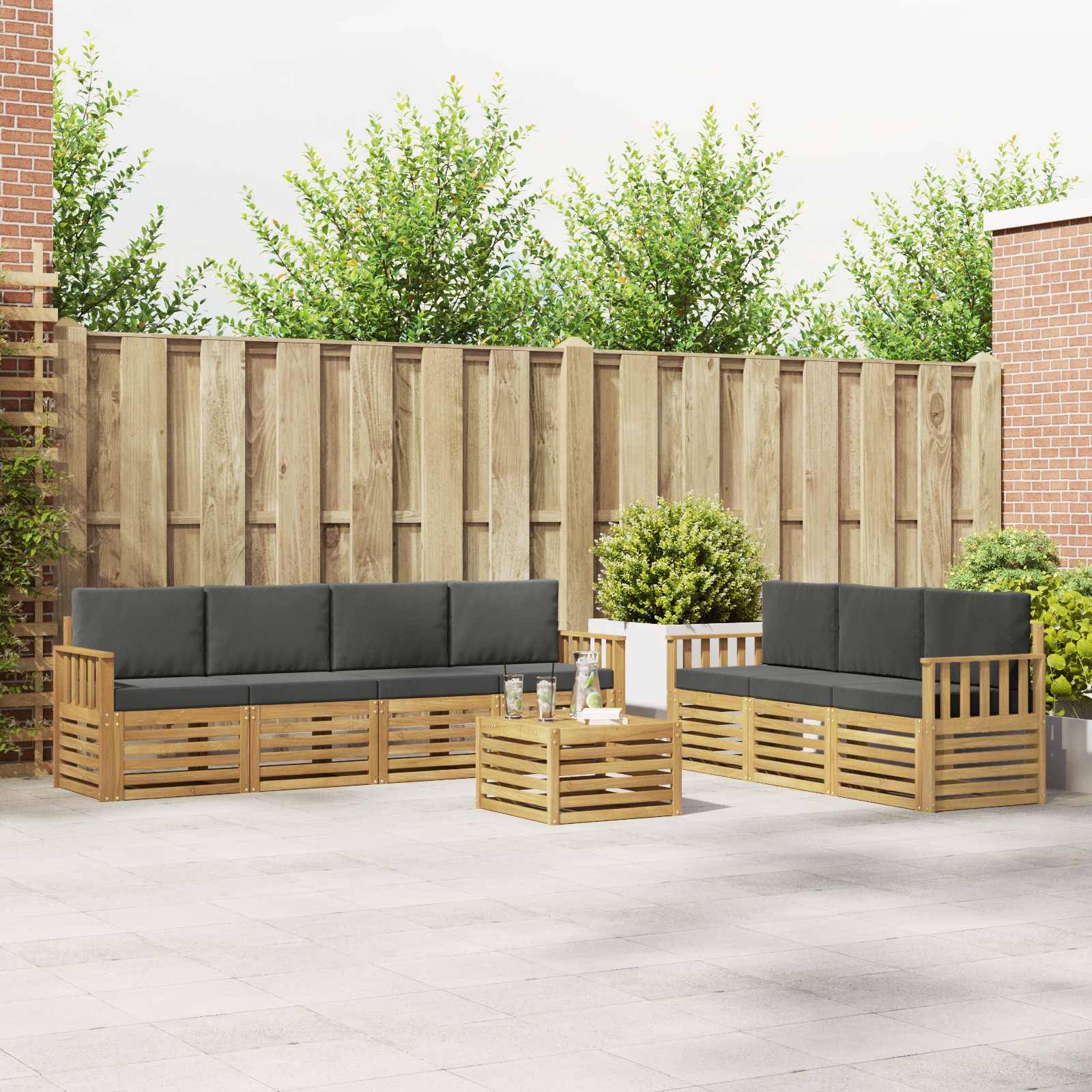Outdoor-Sitzbereich auf einer Terrasse mit zwei Holzsofas, passendem Couchtisch, Topfpflanze und hohem Zaun in einem Innenhof.