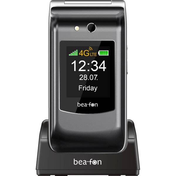 Ein schwarzes Bea-fon Klapptelefon auf einer Ladestation, das auf dem Display 12:34, 28.07., Freitag, 4G LTE und ein Batteriesymbol anzeigt.