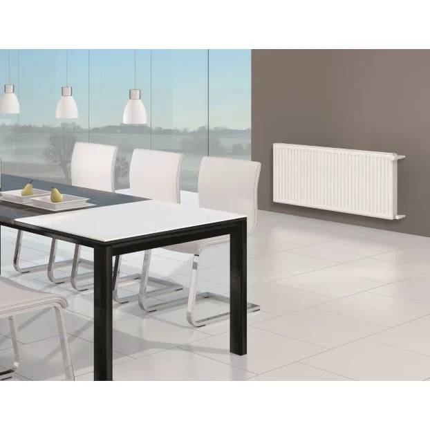 Modernes Esszimmer mit weißen Stühlen und Tisch neben einem an der Wand montierten weißen Heizkörper; große Fenster und Pendelleuchten im Hintergrund.