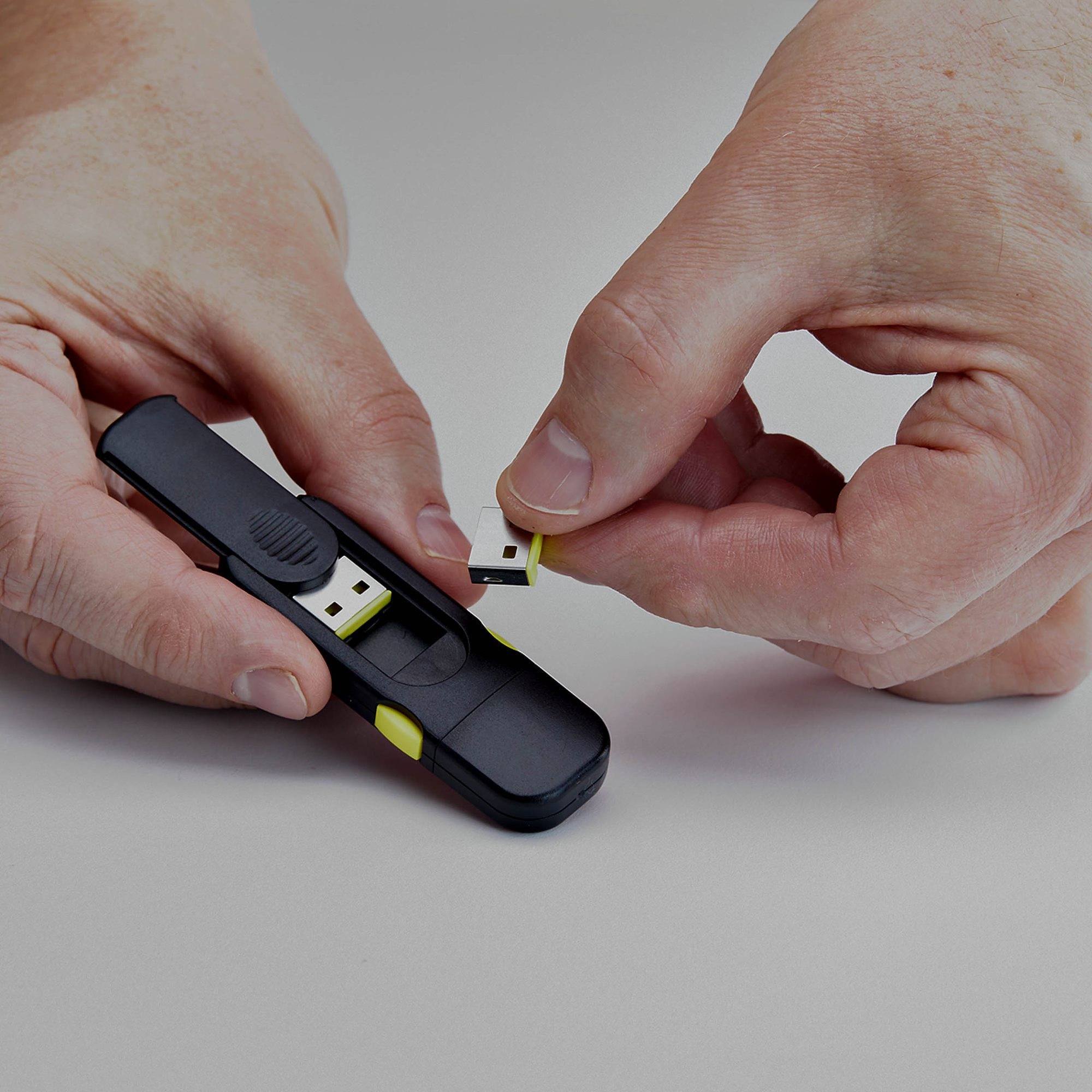 Hände, die einen kleinen USB-Wireless-Empfänger in einen schwarzen USB-Stick auf einer ebenen Oberfläche einführen.