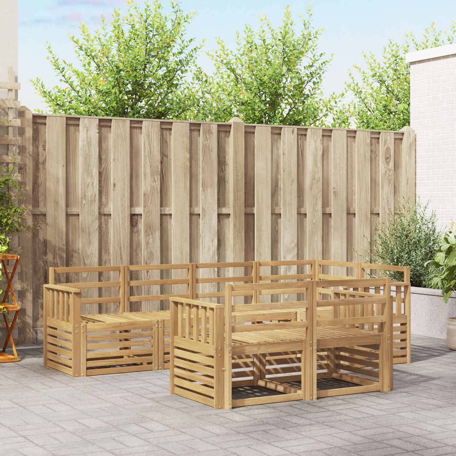 Holzgarnituren für den Außenbereich, angeordnet in einem Patio-Innenhof vor einem hohen Zaun und Grünflächen.