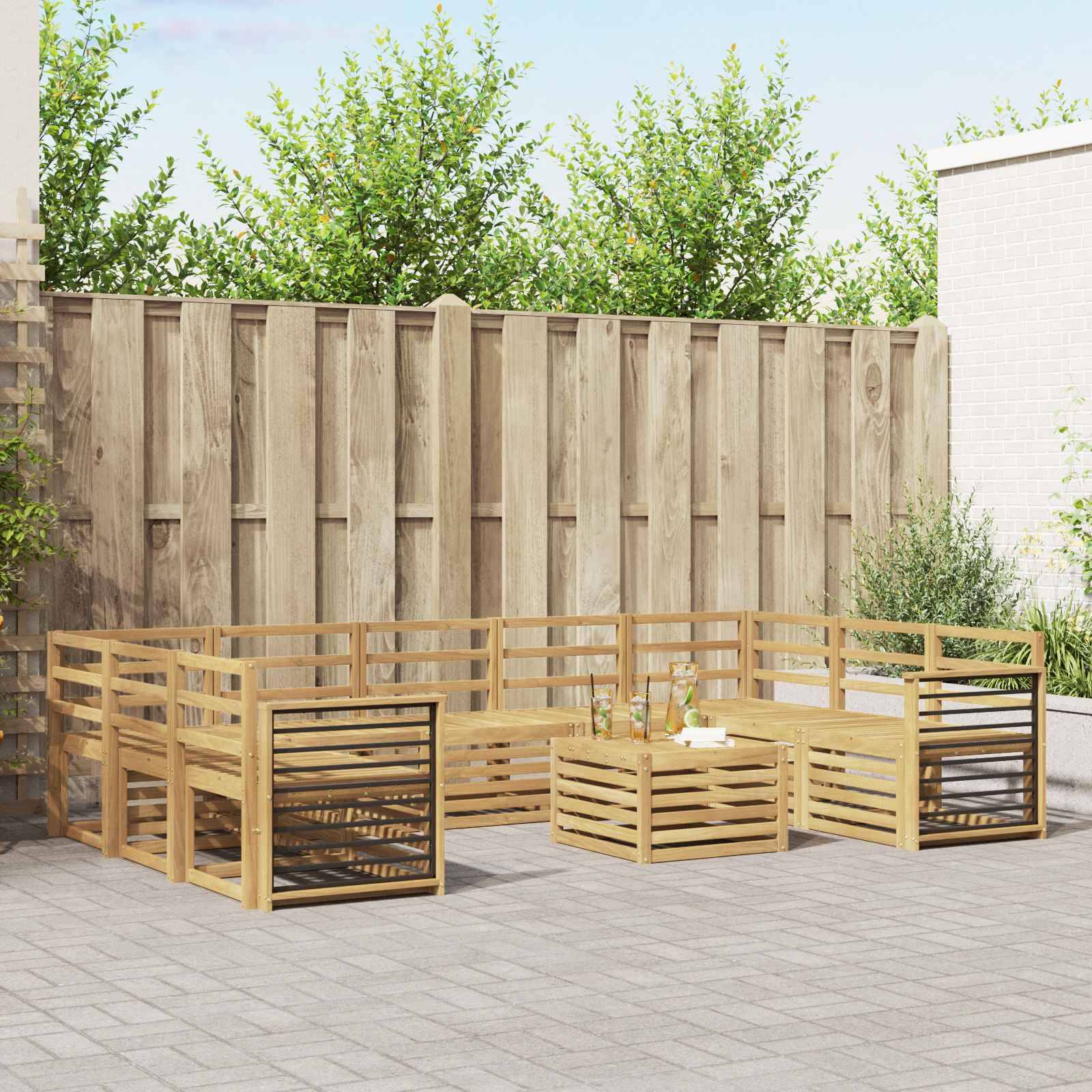 Modulares Outdoor-Sitzset aus Holz mit Latten-Bänken und Couchtisch auf einer gepflasterten Terrasse neben einem Holzzaun und Grünflächen.