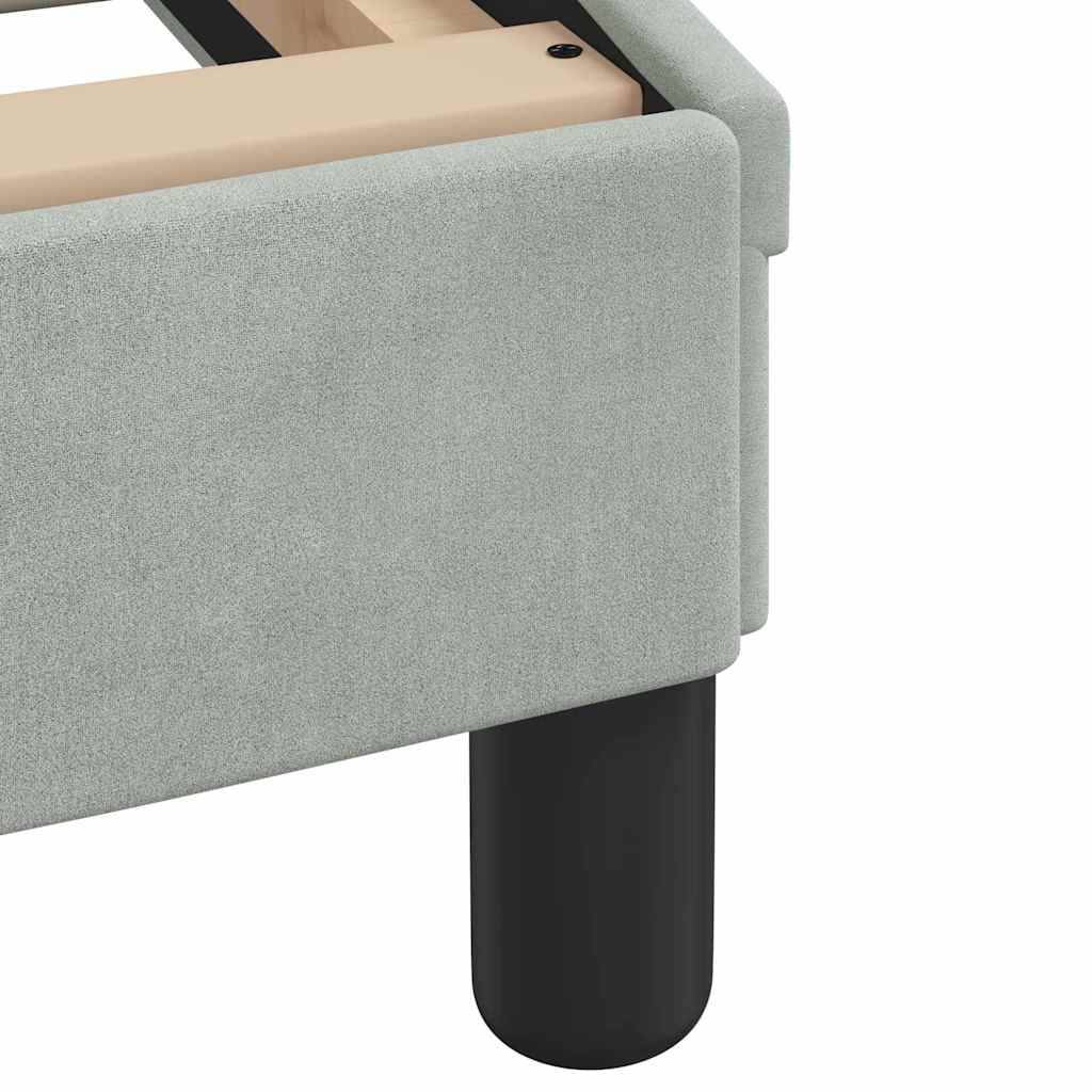 Nahaufnahme einer Ecke eines hellgrau gepolsterten Betts oder Sofas mit einem schwarzen zylindrischen Bein und einem beigefarbenen oberen Rahmen auf weißem Hintergrund.