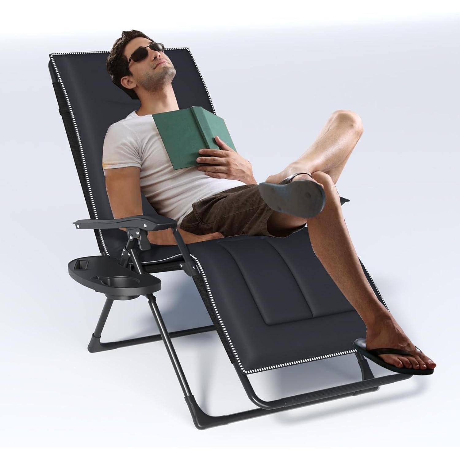 Mann, der sich in einem schwarzen Relaxsessel entspannt, trägt Sonnenbrille und hält ein Buch, mit einem kleinen angebrachten Seitentablett.