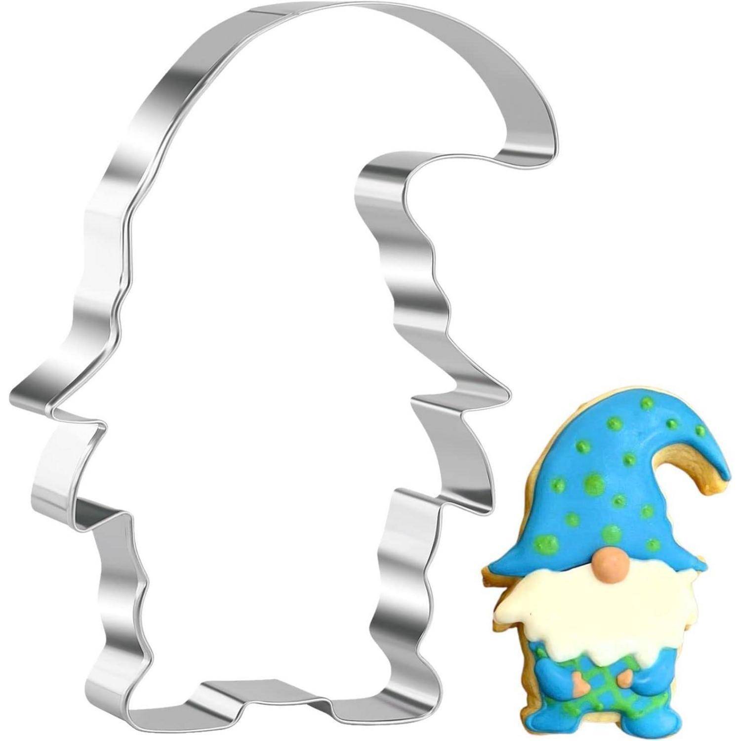 Metallstanzform in Gnomsilhouette neben einem dekorierten blau-weißen Gnomkeks auf weißem Hintergrund.