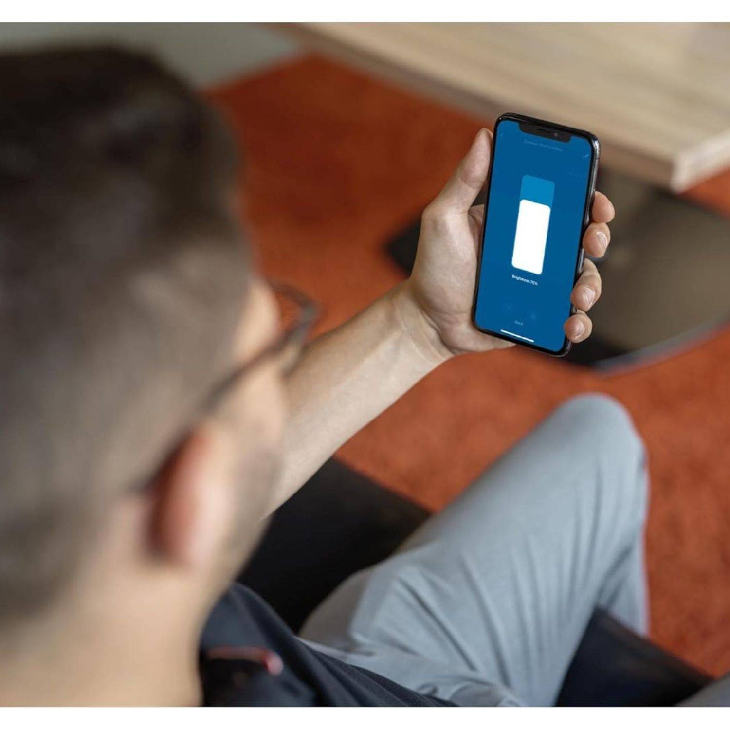 Person, die ein Smartphone betrachtet, das einen blauen Bildschirm mit einem weißen Batteriesymbol anzeigt, was auf eine Lade- oder Stromstatusmitteilung hindeutet.
