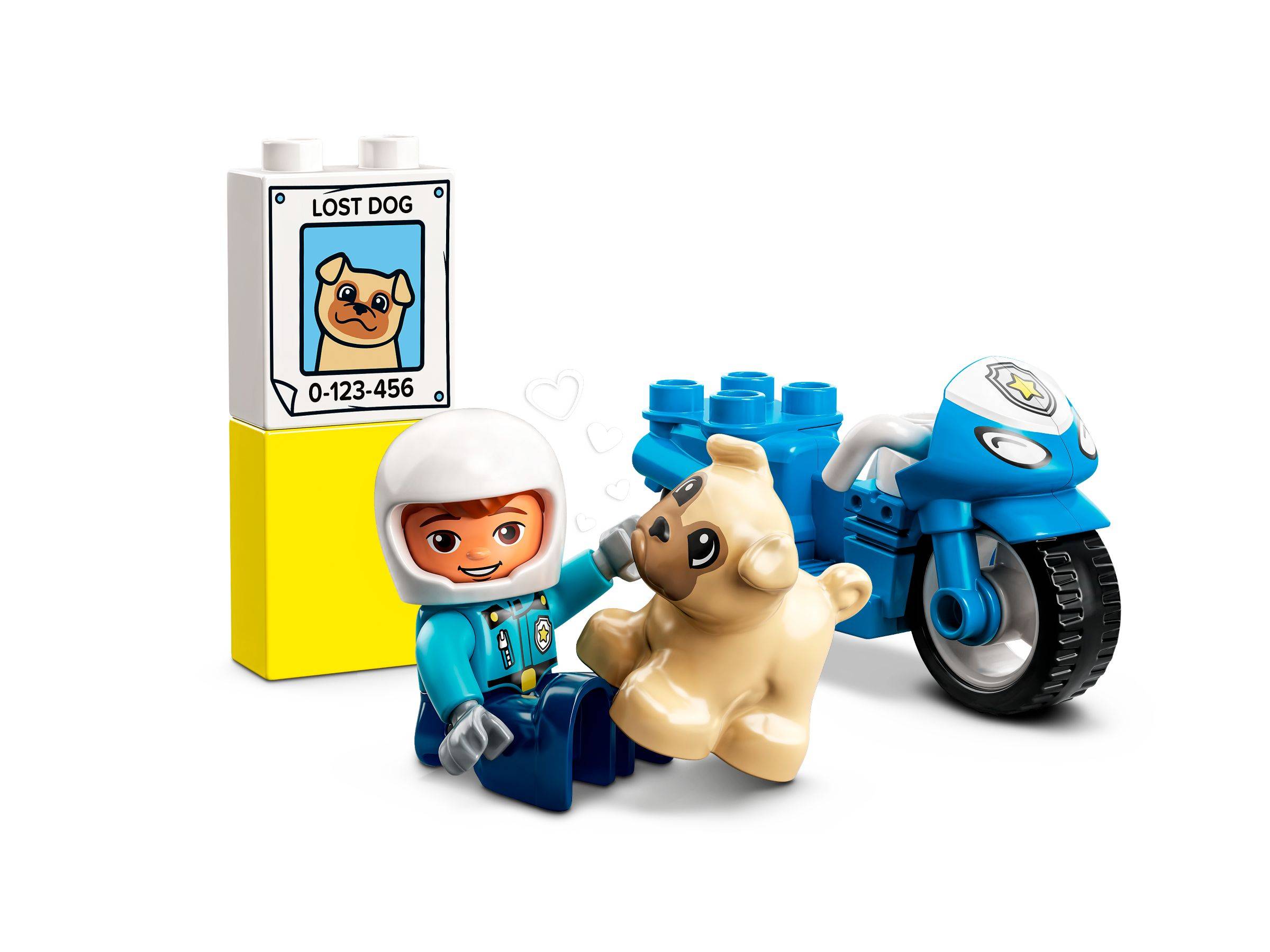 Eine LEGO-ähnliche Minifigur in einem Helm sitzt mit einem beigen Hund neben einem blauen Motorrad, neben einem Plakat „VERMISSTER HUND