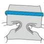 Hände drücken auf ein kleines Papierpaket oder einen Umschlag, mit einem blauen Band über dem oberen Teil und Bewegungslinien, die ein Quetschen oder Öffnen andeuten.