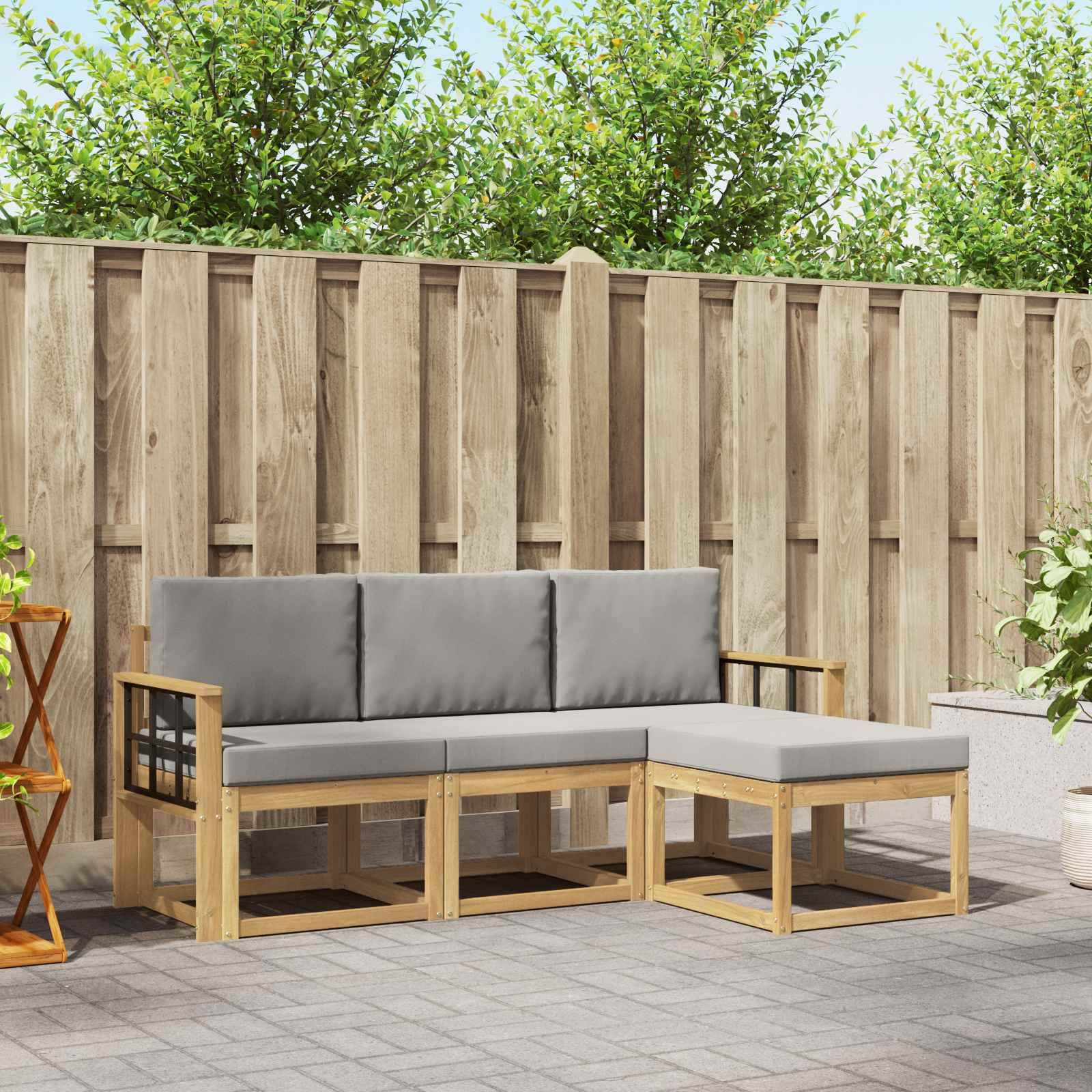 Outdoor-Ecksofa-Set mit hellem Holzrahmen, grauen Kissen und Ottomane vor einem Holzzaun und Natursteinplatten.