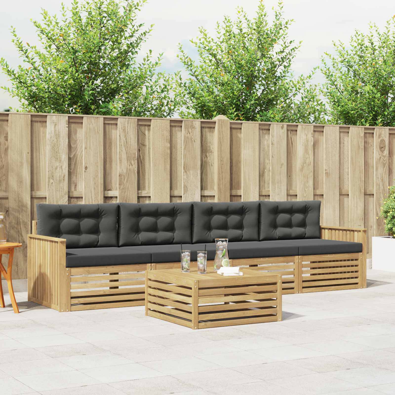 Outdoor-Terrassenmöbel-Set mit schwarz gepolstertem Holzsofa, passendem Couchtisch und Gartensetting mit Zaun im Hintergrund.