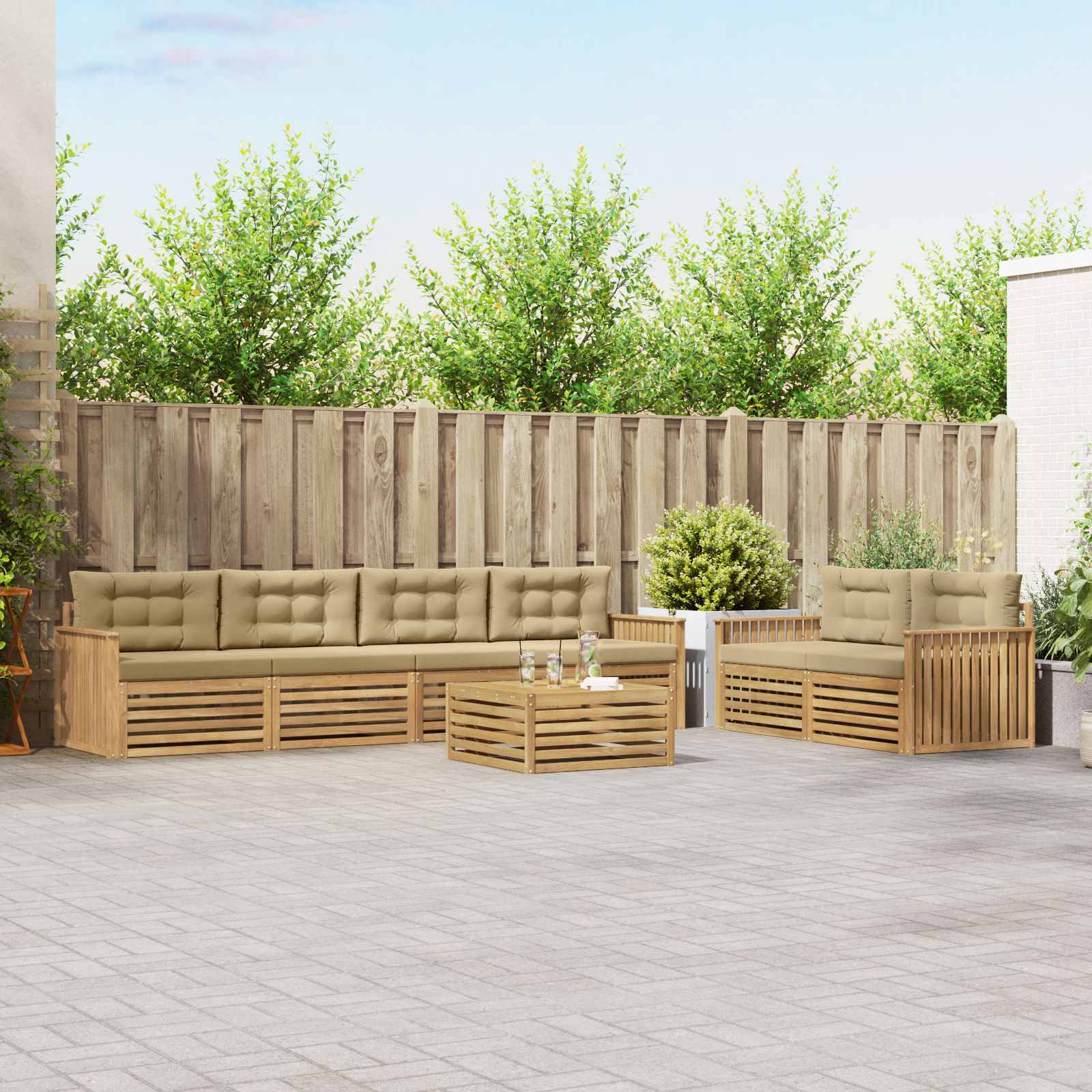 Outdoor-Terrasse mit hölzerner Sitzbankgruppe, Couchtisch und Topfpflanzen vor einem Sichtschutzzaun.