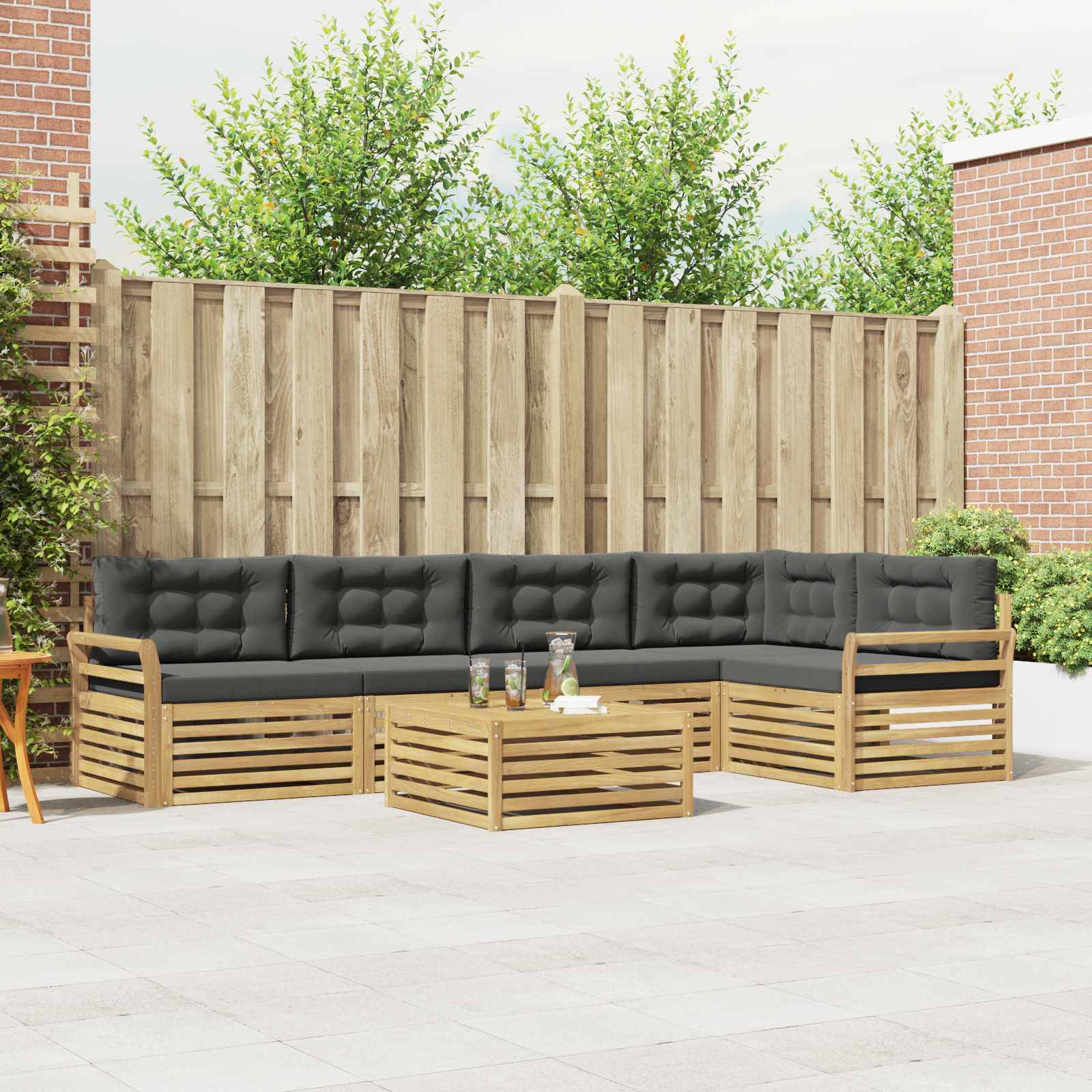 Outdoor-Terrassensitzgruppe mit schwarzem gepolstertem Holzsektional und passendem Couchtisch in einem eingezäunten Garten.