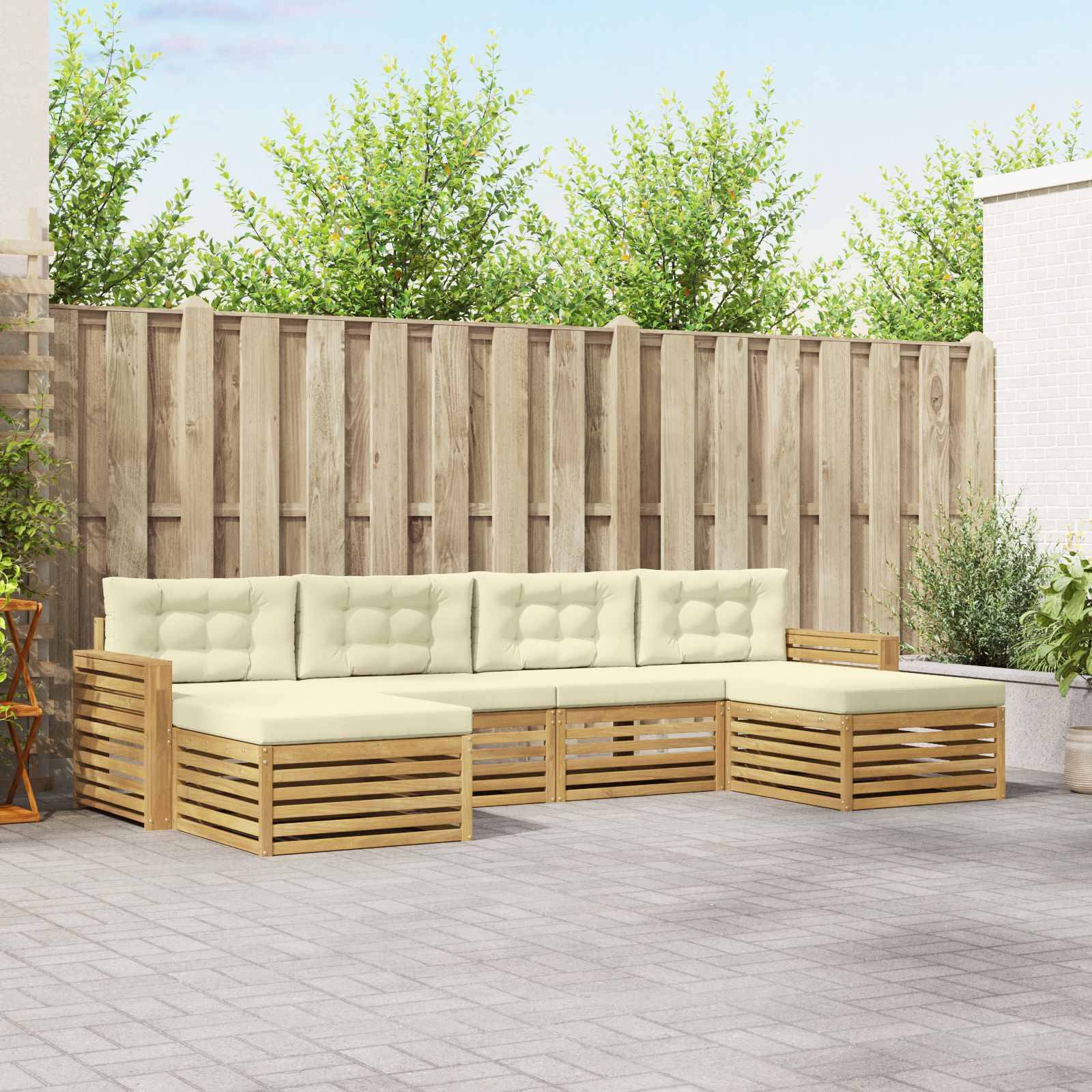 Gartensektionalsofa für die Terrasse mit hellen Kissen und Holzlattenbasis an einer Gartenzaunwand