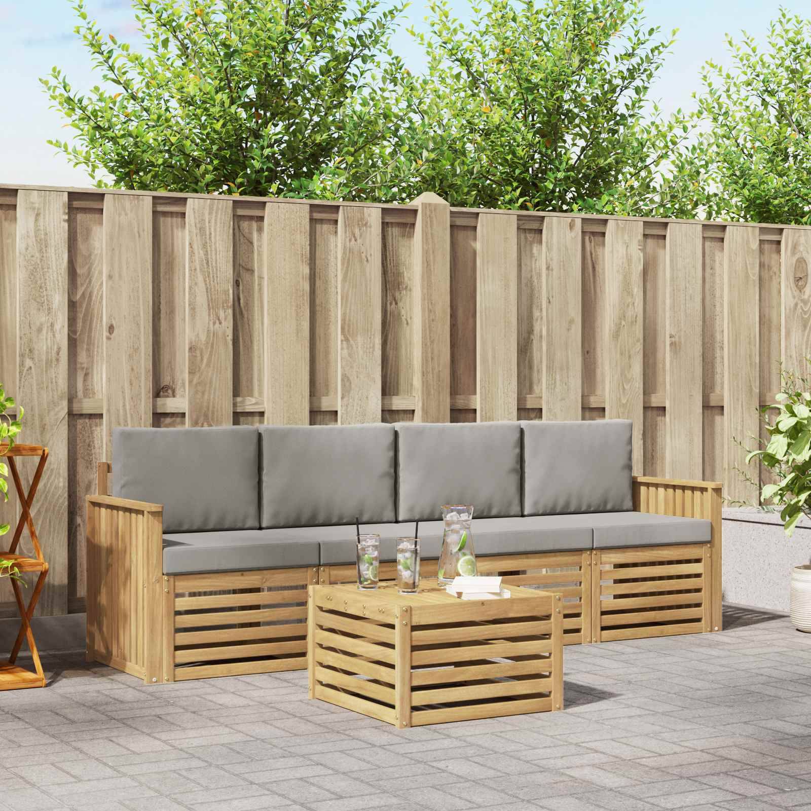 Außenbereich mit Sitzecke auf einer Terrasse, bestehend aus einem hölzernen Dreisitzer-Sofa, passendem Couchtisch und Topfpflanzen vor einem Holzzaun.