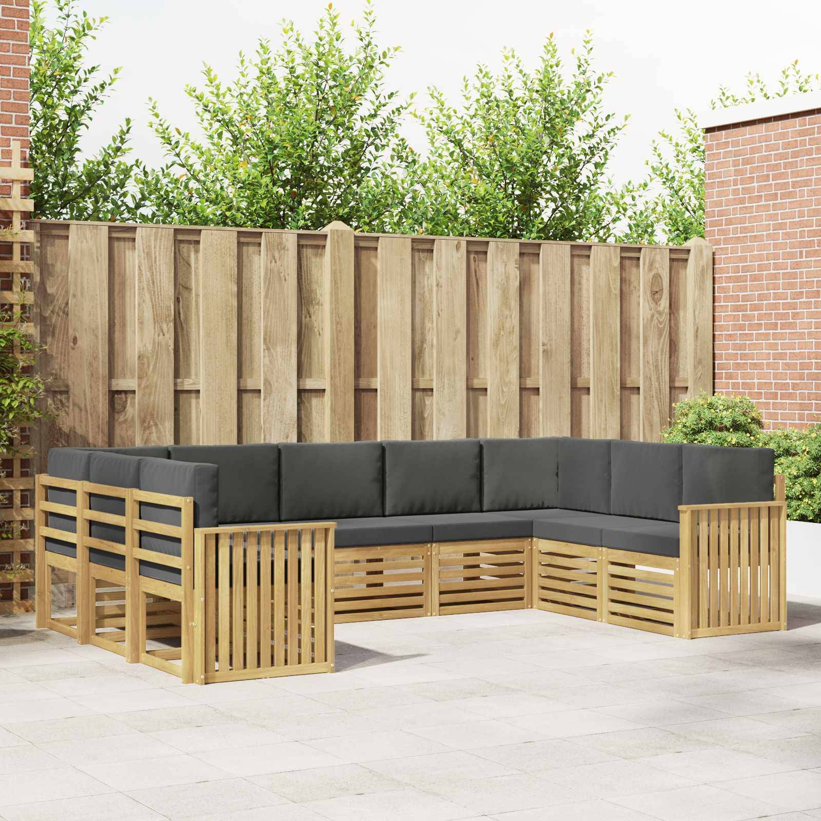 Outdoor L-förmiges Holz-Ecksofa mit dunklen Polstern auf einer Terrasse, vor einem Holzzaun und Backsteinmauern.