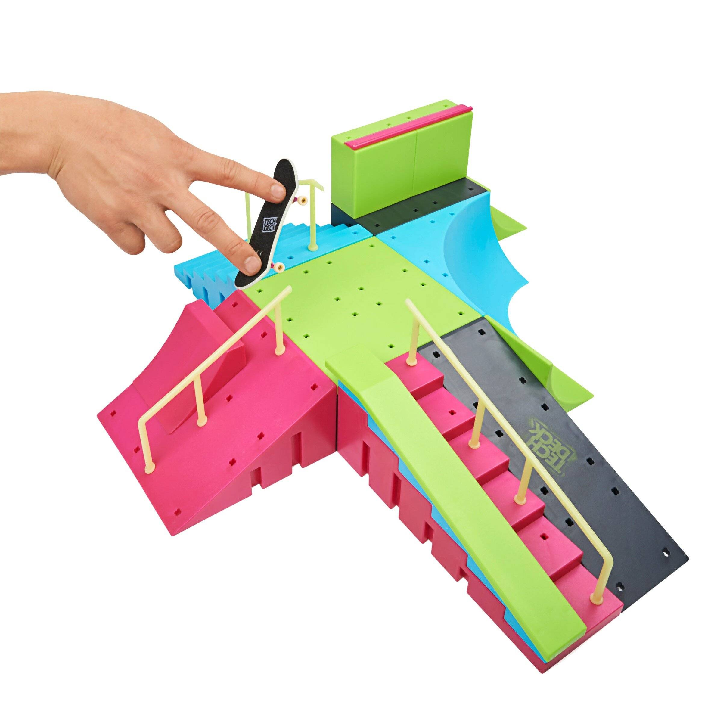 Hand drückt einen kleinen schwarzen Marker auf ein farbenreiches 3D-Puzzleboard mit verbundenen Rampen und Wegen, auf weißem Hintergrund gezeigt.