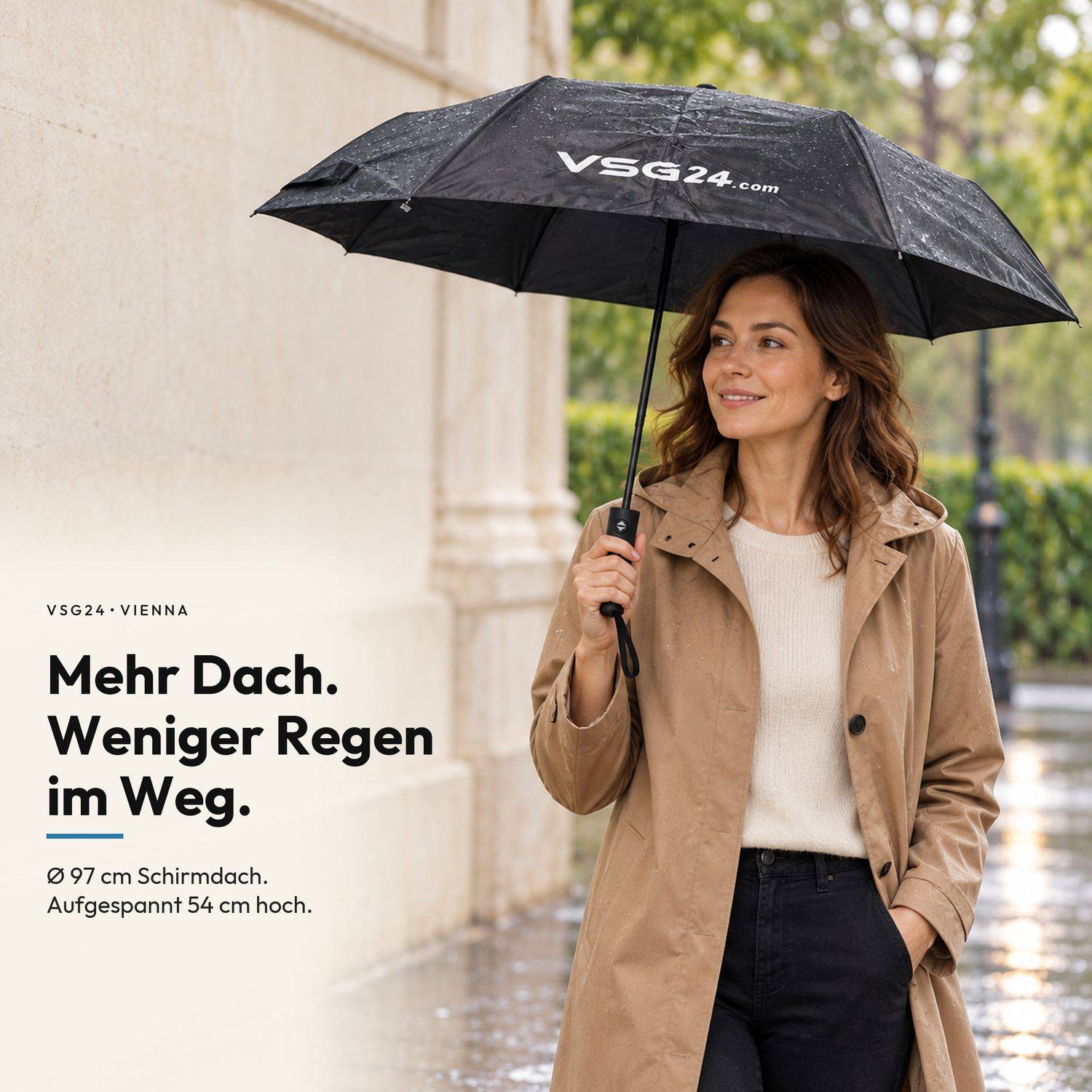 Frau, die einen schwarzen Regenschirm mit der Marke „VSG24.com" auf einer regnerischen Straße hält; deutscher Text sagt „Mehr Dach. Weniger Regen unterwegs."" und vermerkt 97 cm Baldachin, 54 cm wenn geöffnet.