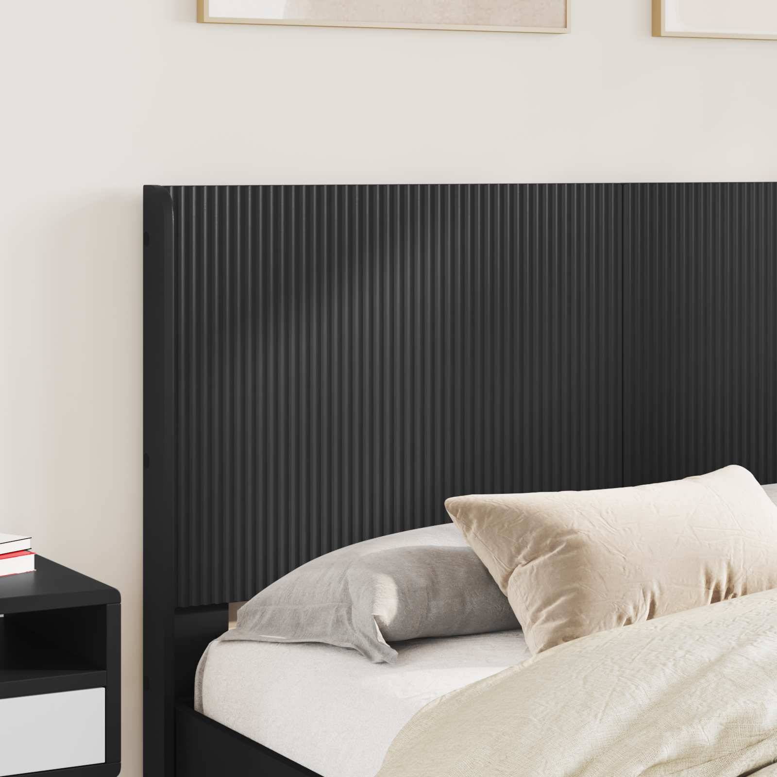 Moderne Schlafzimmerecke mit schwarzem Kopfteil mit Riefung, Bett mit weißen und grauen Kissen und schwarzem Nachttisch.