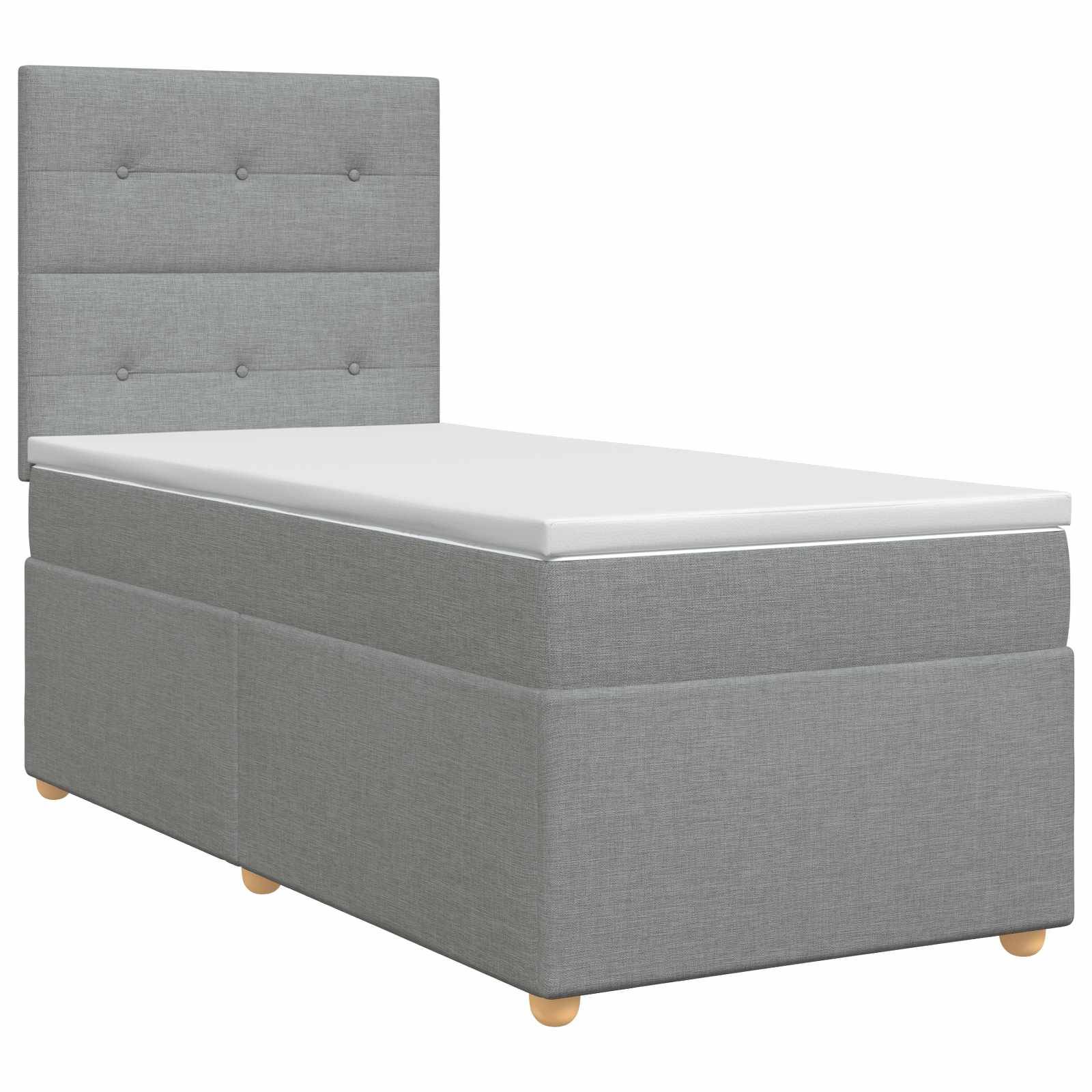 Grau gepolstertes Einzelbett mit gepolstertem, gestepptem Kopfteil und weißer Matratze auf kurzen Holzbeinen.