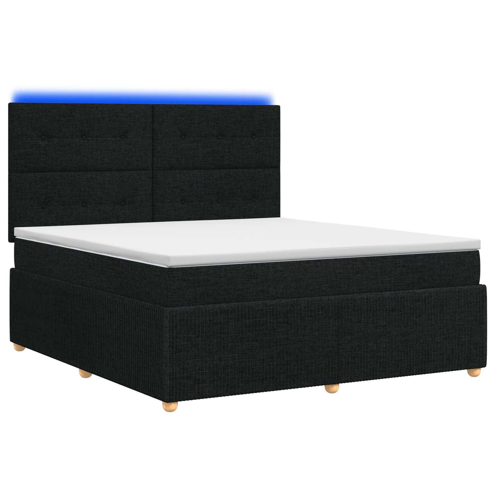 Schwarz gepolstertes Bett mit weißer Matratze und gepolstertem Kopfteil auf weißem Hintergrund.
