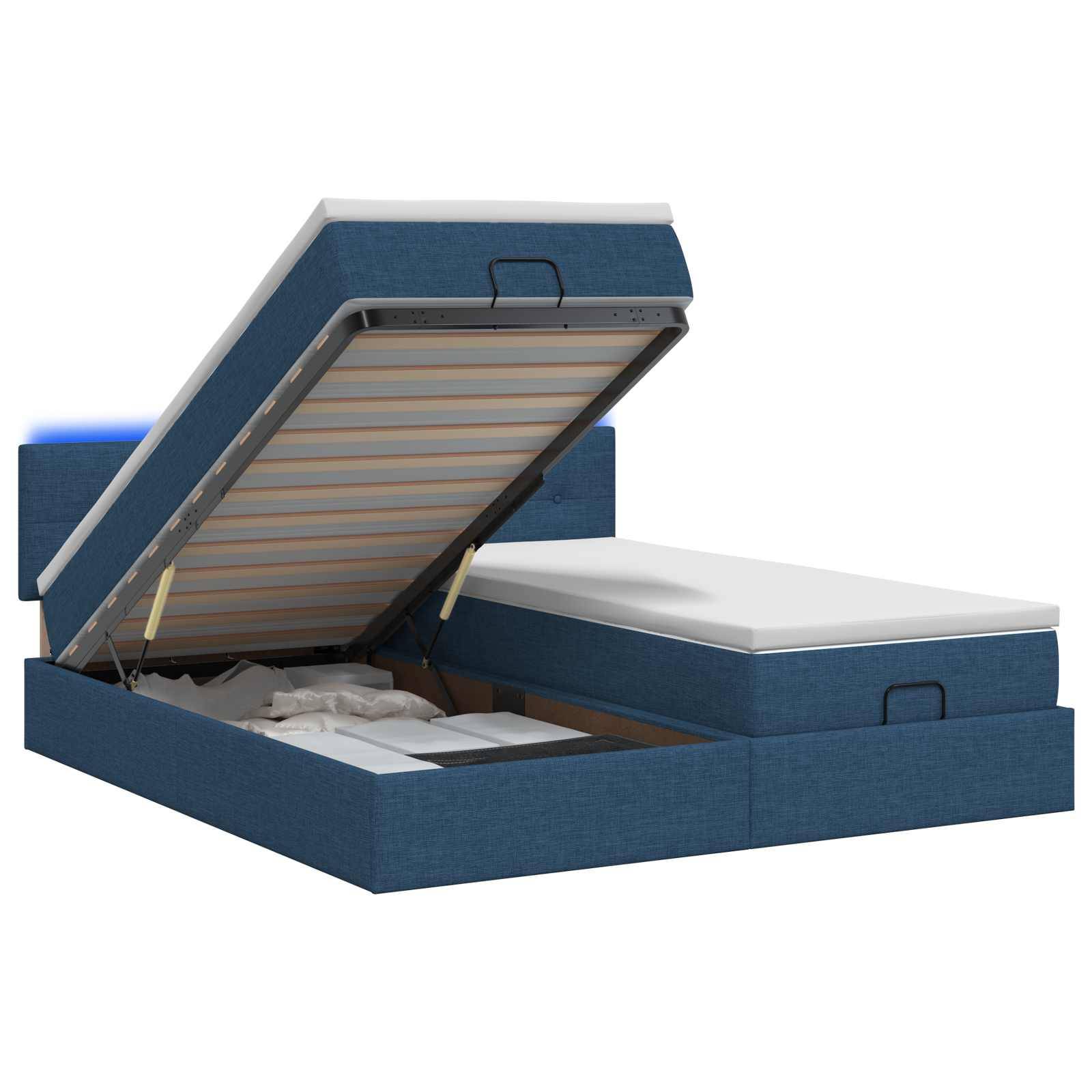 Blaues gepolstertes Speicherbett mit geöffnetem Matratzenlifter, das das Unter-Bett-Fach und die Stützlatten offenbart.