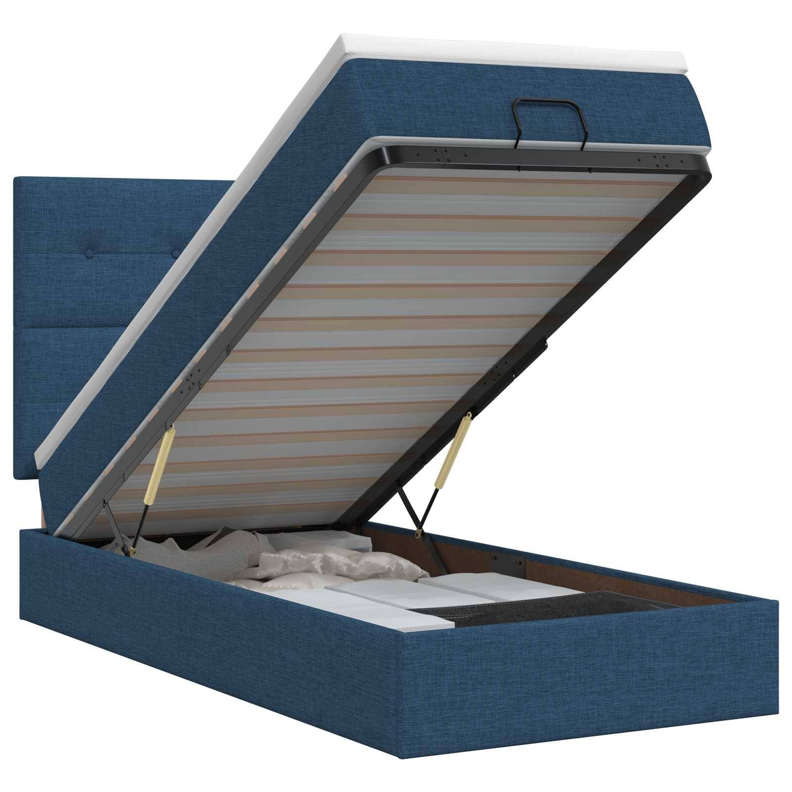 Blau gepolstertes Speicherbett mit klappbarer Matratzenablage, die das Unter-Bett-Staufach offenlegt.
