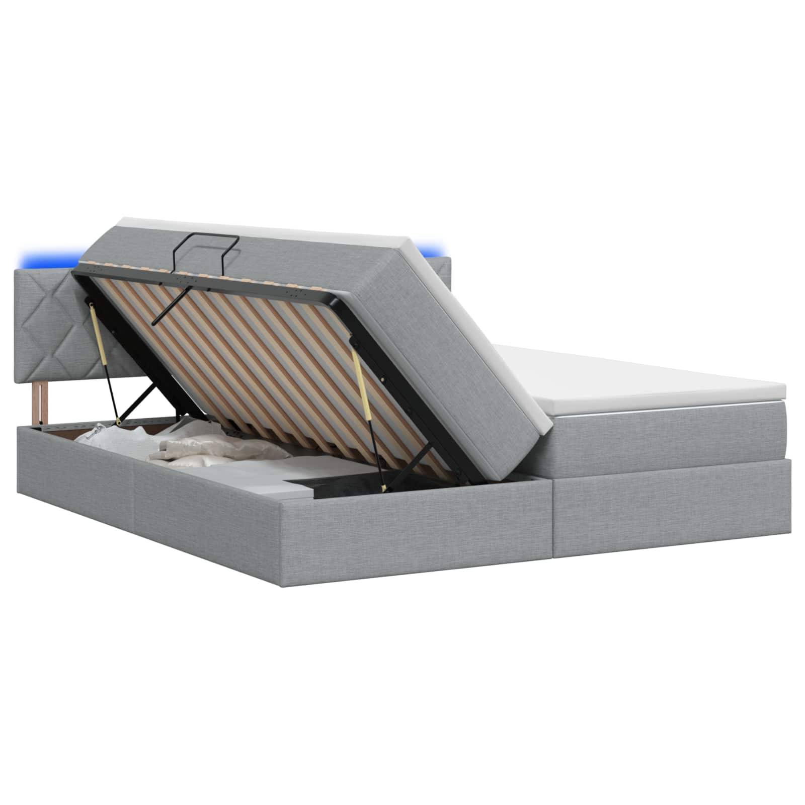Grau gepolstertes Bett mit Hubmechanismus zum Hochfahren der Matratze, wobei die Latten-Unterseite und das versteckte Fach darunter sichtbar werden.