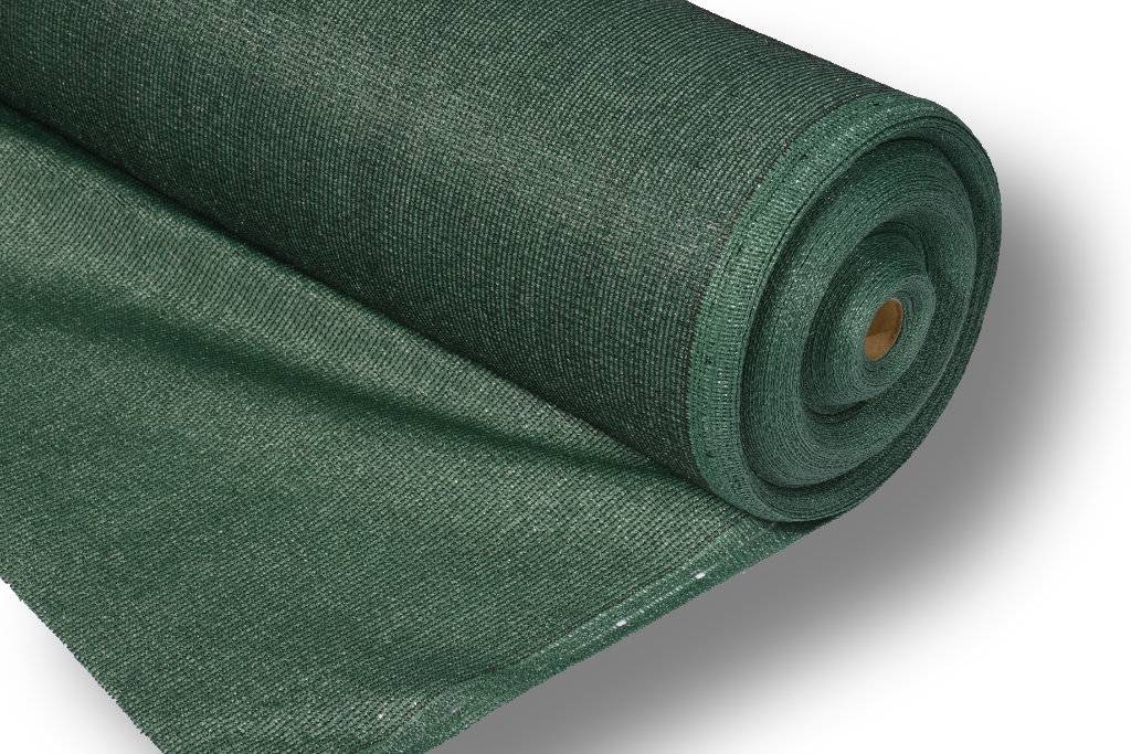 Aufgerollter grüner Schattierstoff oder Meshgewebe auf weißem Hintergrund, das die Materialtextur und die aufgerollte Kante zeigt.