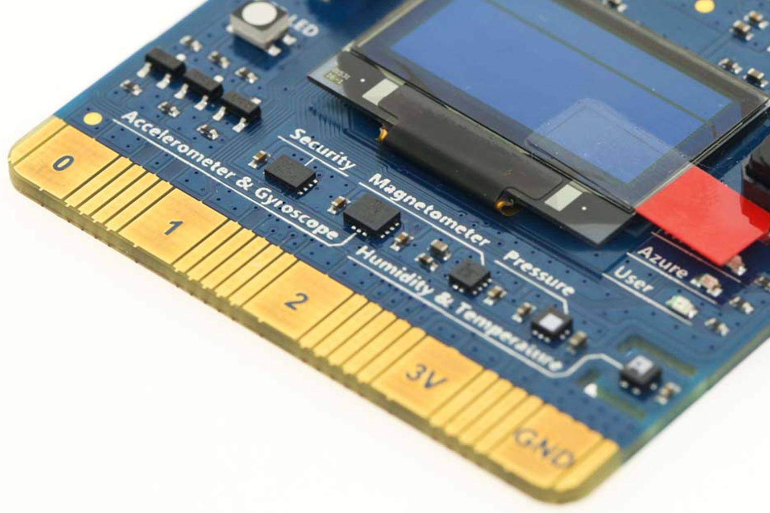 Nahaufnahme einer blauen Elektronikplatine mit einem LCD-Bildschirm und beschrifteten Sensormodulen, einschließlich Beschleunigungsmesser, Gyroskop, Sicherheit, Magnetometer, Druck, Luftfeuchtigkeit und Temperatur.