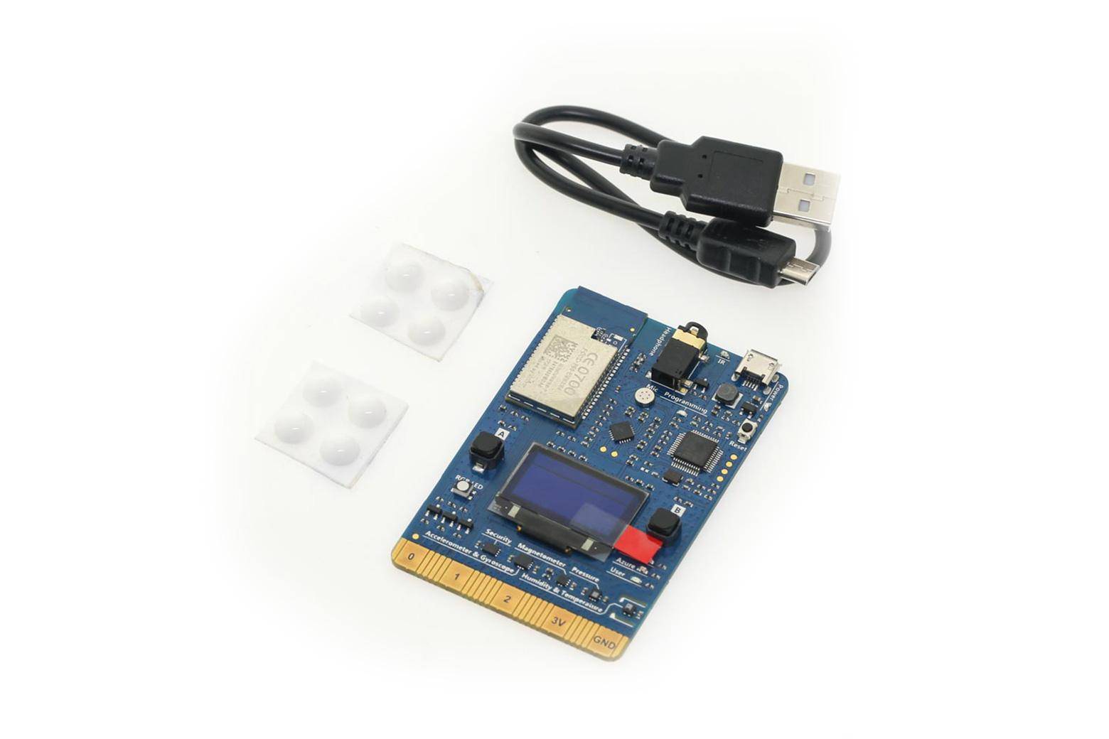 Blaue elektronische Leiterplatte mit kleinem Display, USB-Kabel und zwei Haftpads auf weißem Hintergrund.