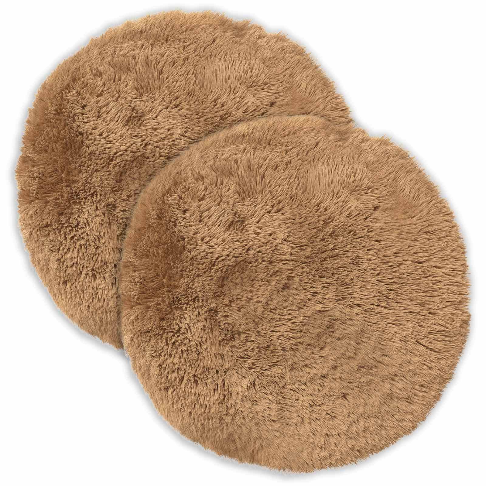 Zwei runde, beige Kunstfell-Sitzkissen, die sich auf weißem Hintergrund überlappen.