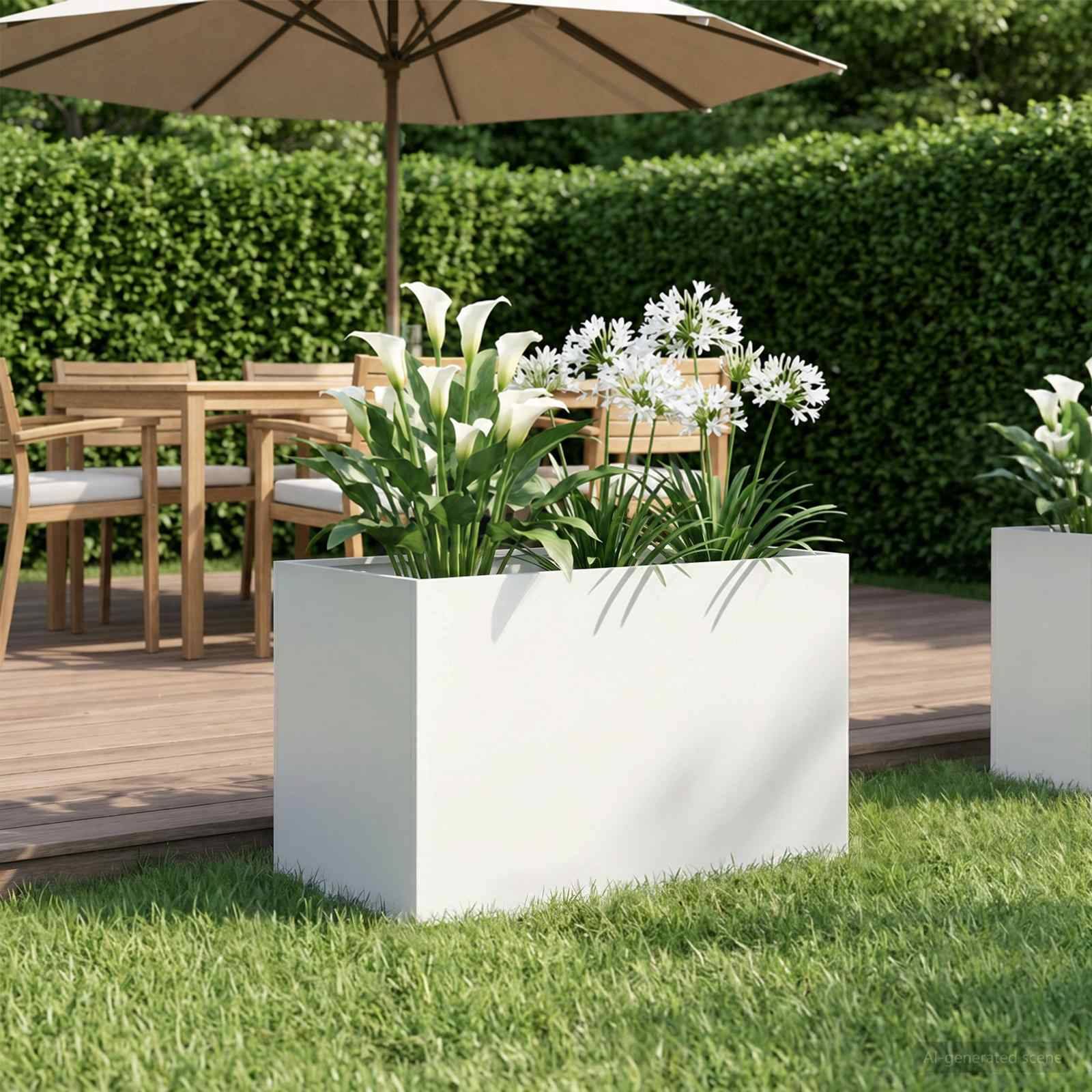 Weiße rechteckige Pflanzschale mit Calla-Lilien und weißen Blüten auf einer grasbewachsenen Terrasse neben Gartenmöbeln aus Holz und einem Sonnenschirm.