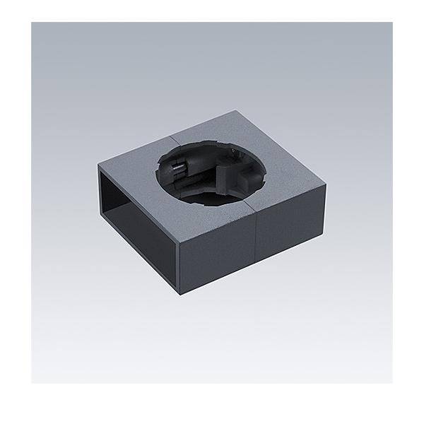 Dunkelgrauer quadratischer Metallblock mit einer kreisförmigen Aussparung oben und einer rechteckigen Öffnung an der Seite, dargestellt auf hellem Hintergrund.