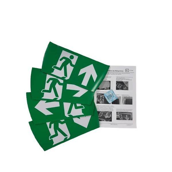 Stapel grüner Notausgangschilder mit weißem Laufmann und Richtungspfeilen neben einem gedruckten Merkblatt.