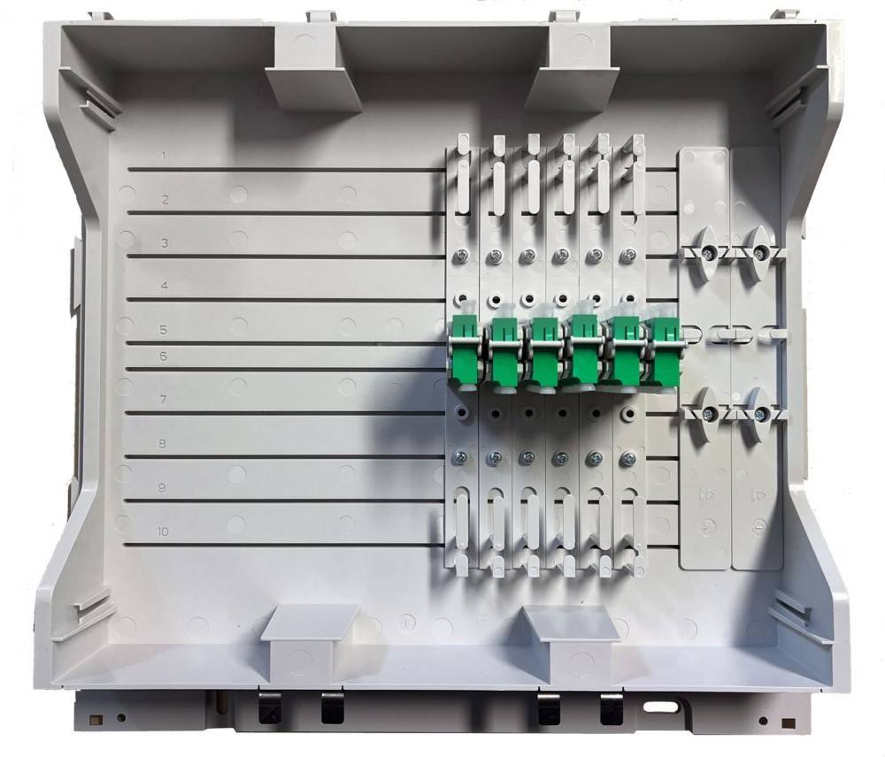 Offenes Elektroverteilerpanel mit nummerierten Reihen und eingebauten Schaltermodulen, größtenteils leer mit Ausnahme einer zentralen Gruppe von grünen und weißen Schaltern.