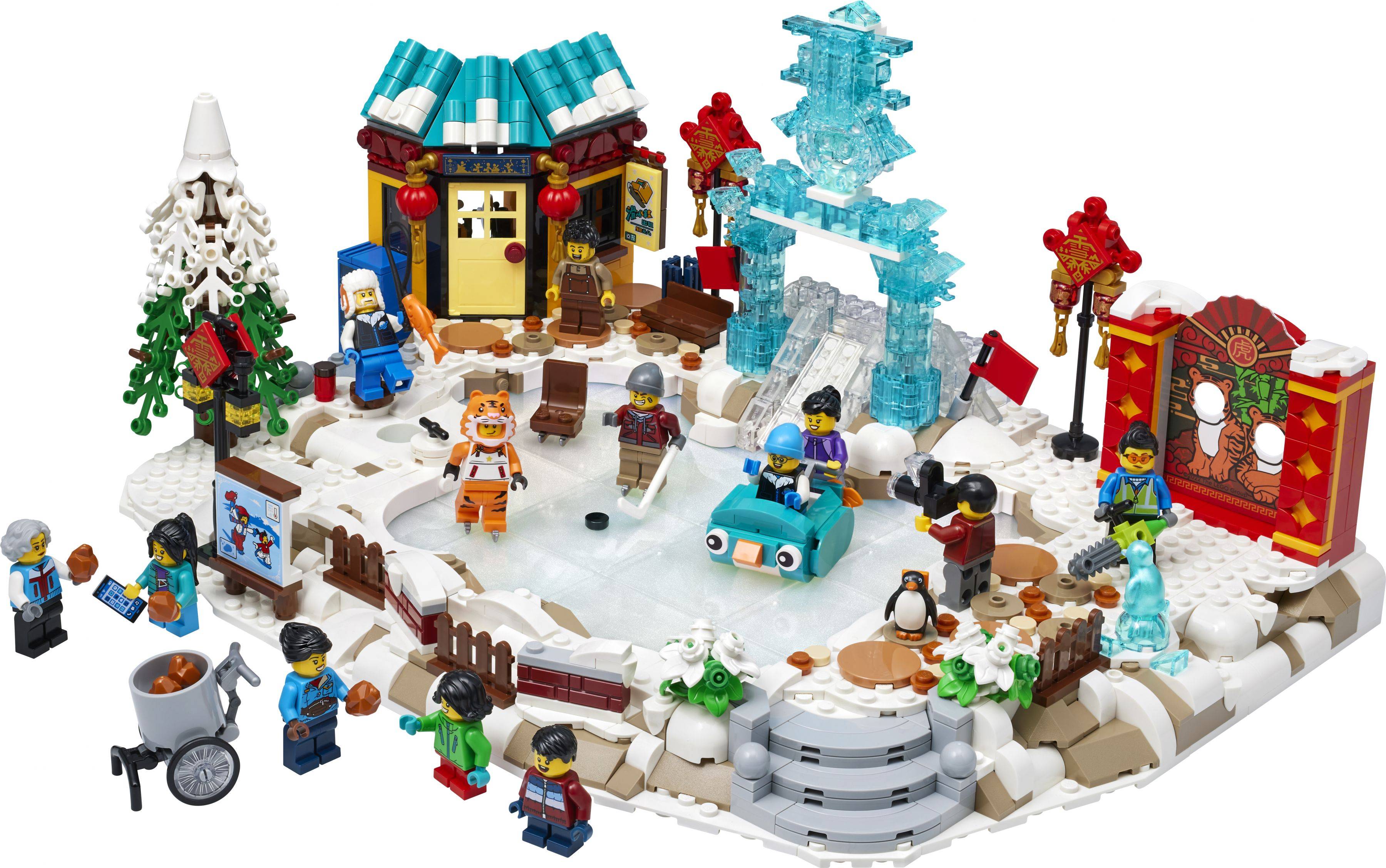 LEGO-Winterdorfszene mit einem gefrorenen Eislaufteich, Feiertagsladen, Eisskulptur, dekorierten Bäumen und Minifiguren, die einen festlichen Markt genießen.