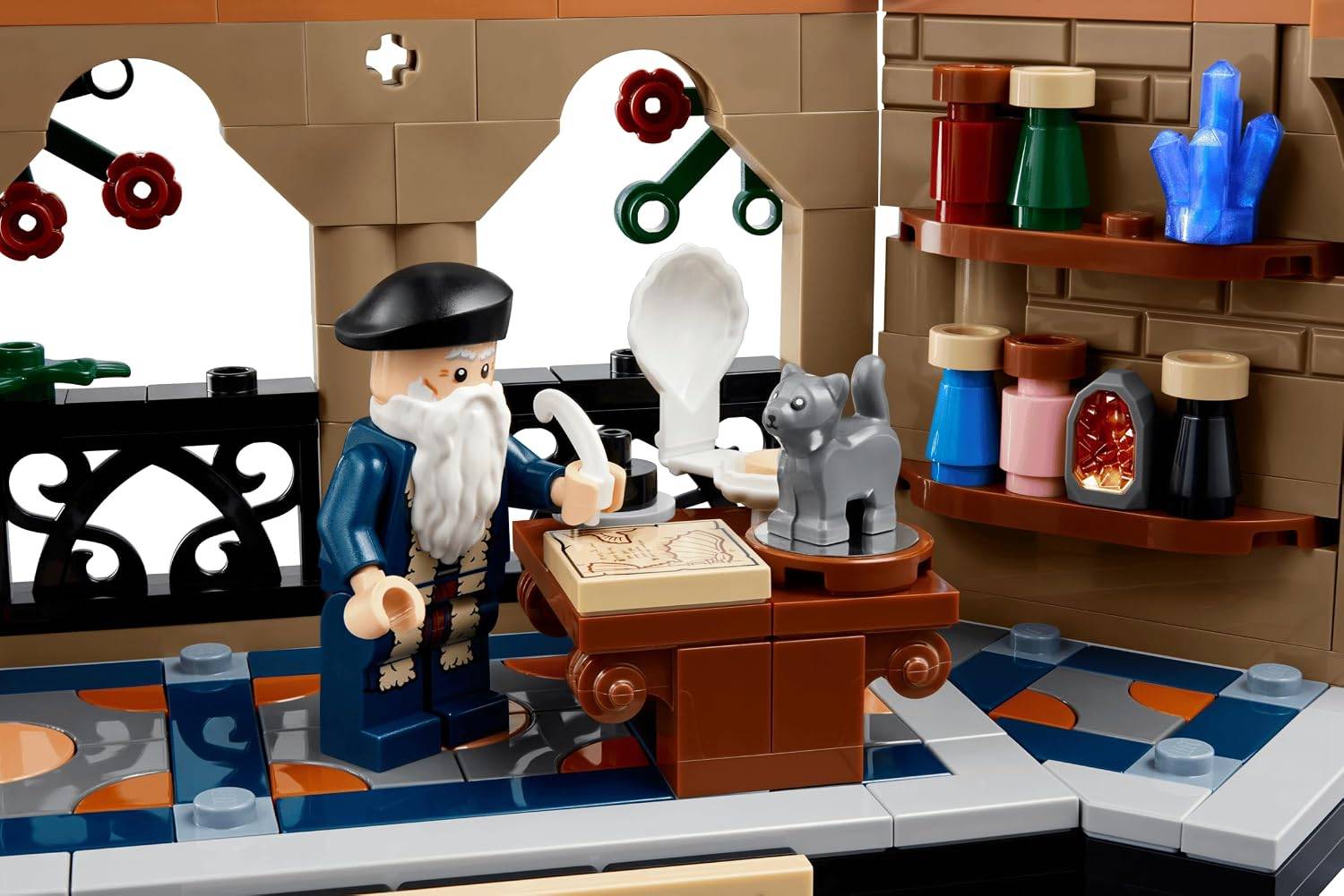 Spielzeugwerkstatt-Szenerie mit einem bärtigen LEGO-Handwerker, der neben einer Werkbank steht, umgeben von Werkzeugen, Regalen mit farbigen Gläsern und einer kleinen grauen Katzenfigur.