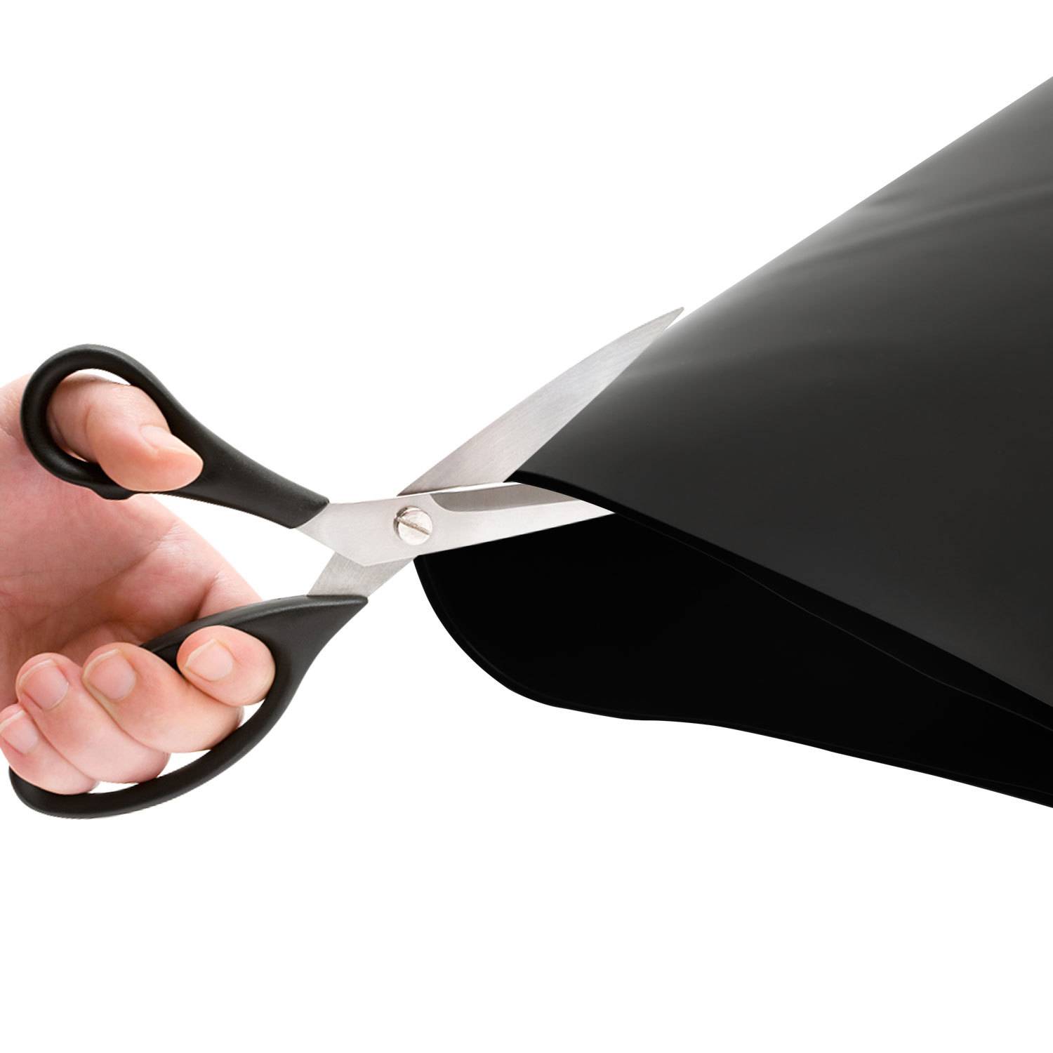 Hand mit Schere, die einen schwarzen Umschlag oder gefaltetes Papier gegen weißen Hintergrund öffnet.