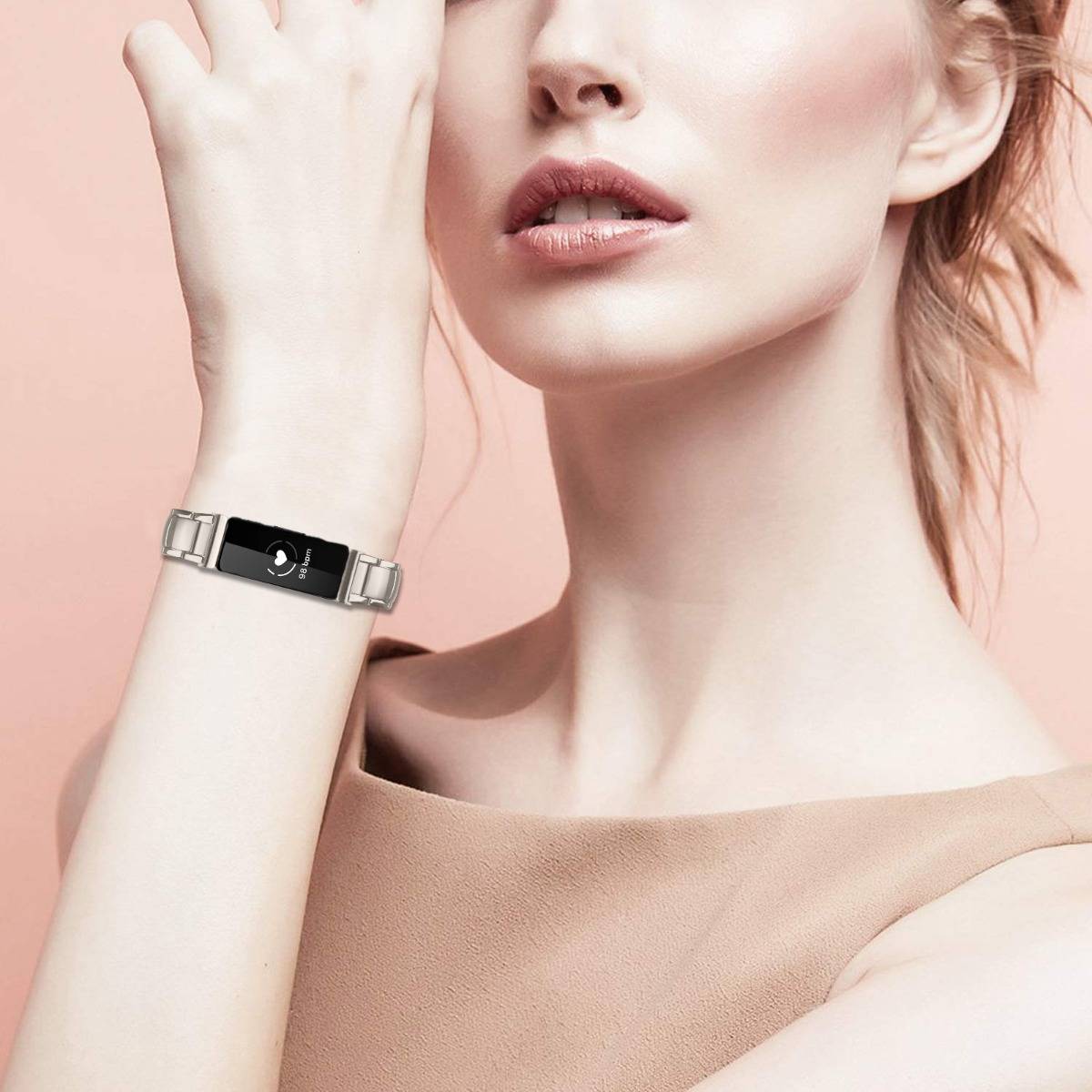 Nahaufnahme einer Frau, die ein silbernes Fitness-Tracker-Armband mit schwarzem Display trägt, das ein Mondsichel-Symbol an ihrem Handgelenk zeigt.