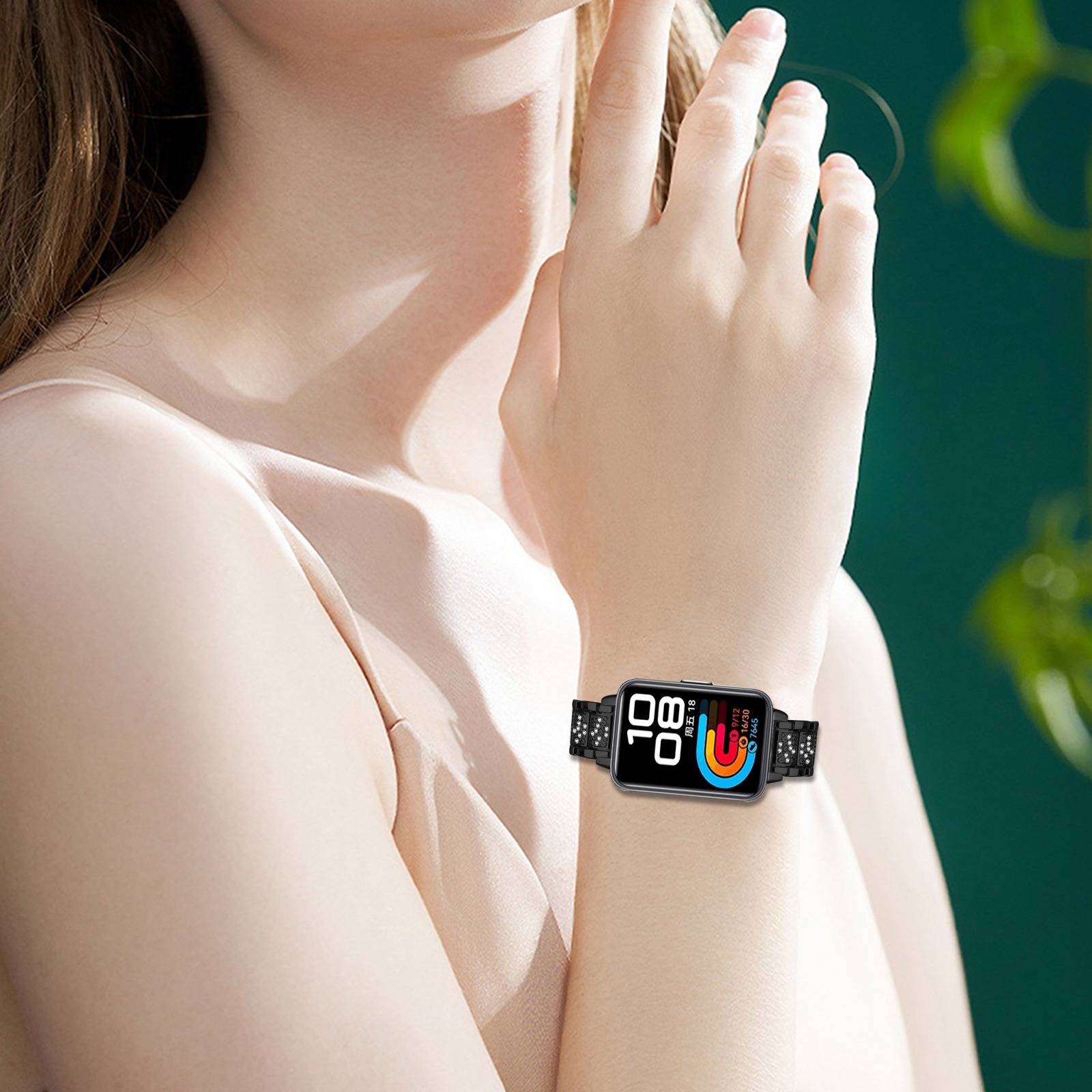 Nahaufnahme einer Frau, die eine Smartwatch mit farbenfrohem digitalen Display am Handgelenk trägt, die Hand erhoben neben ihrem Gesicht.