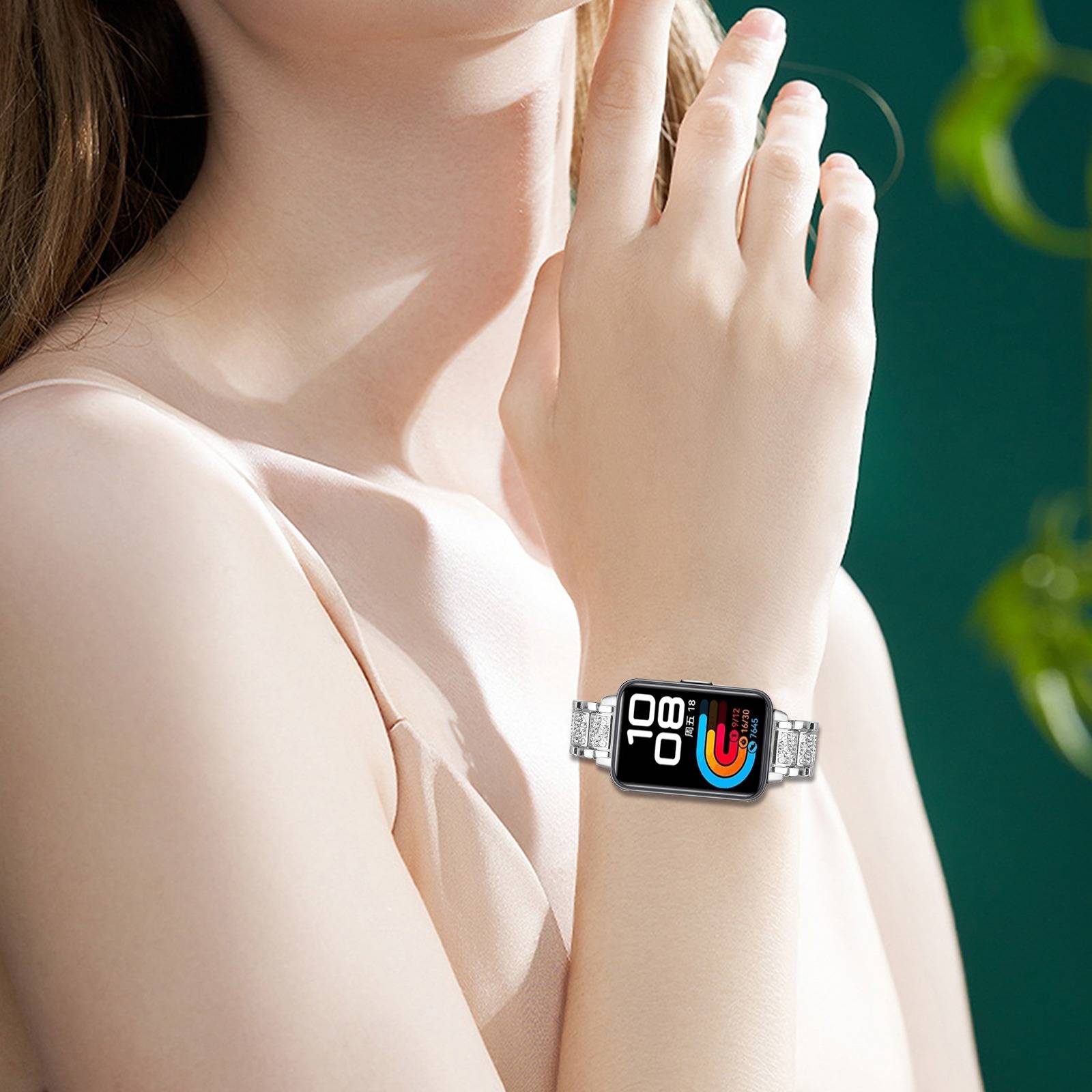 Nahaufnahme einer Frau, die eine Smartwatch mit einem farbenfrohen Fitness-Display auf einem silbernen Armband trägt.