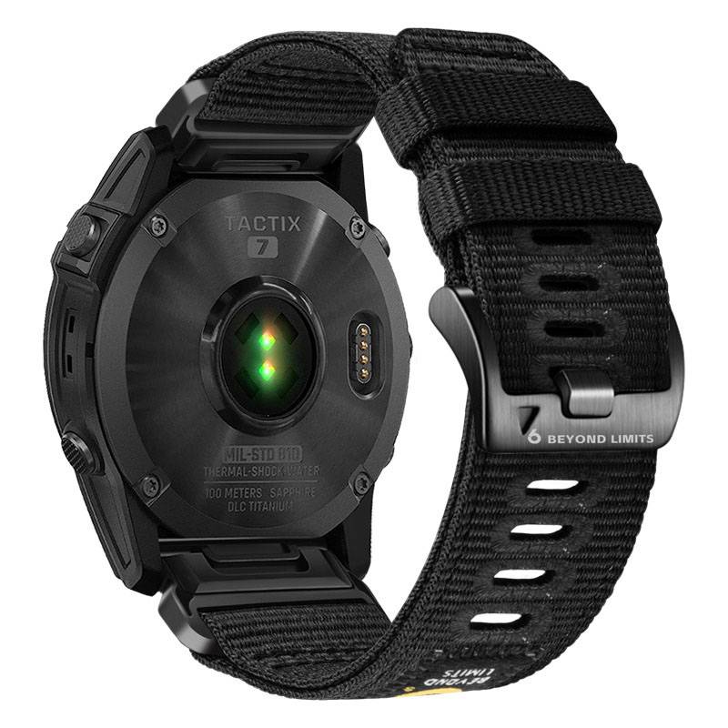 Schwarze Garmin tactix 7 Smartwatch von hinten gezeigt, mit Herzfrequenzsensor, robustem Gehäuse und schwarzem Nylon-Armband mit der Bezeichnung '6 BEYOND LIMITS'.