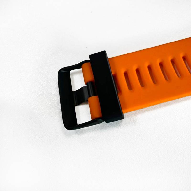Nahaufnahme eines orangefarbenen Gummi-Uhrenarmbands mit einer schwarzen Schnalle auf weißem Hintergrund.