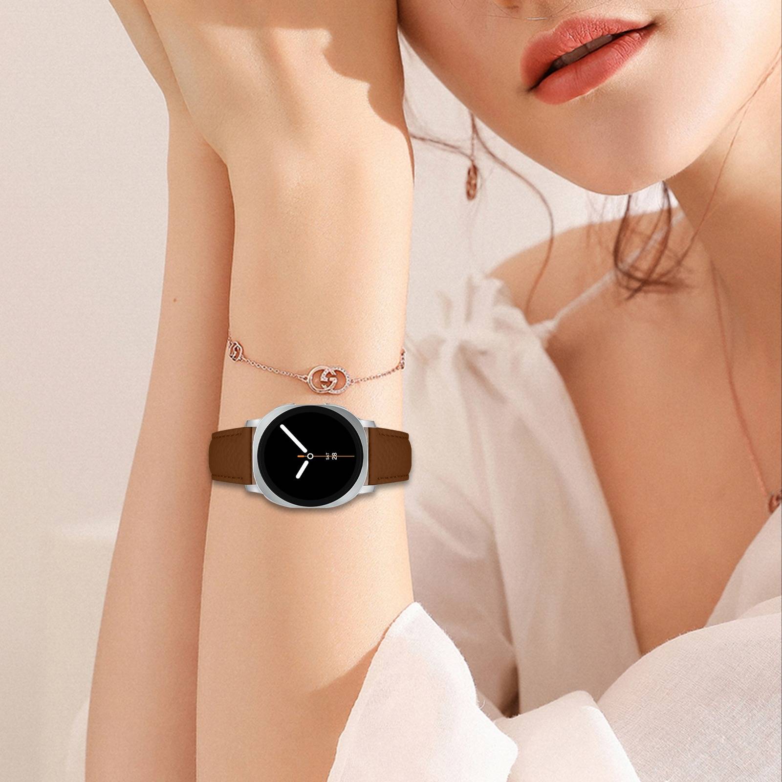 Nahaufnahme einer Frau, die eine runde schwarze Armbanduhr mit braunem Armband und silbernem Gehäuse trägt, mit Schmuck und einer weißen Bluse.