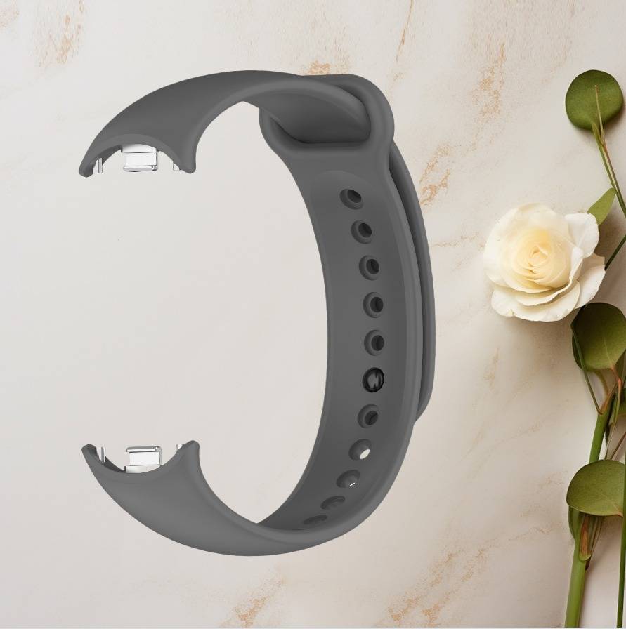 Graues Silikonarmband mit perforierten Löchern, dargestellt auf hellem Marmor-Hintergrund neben einer weißen Rose.