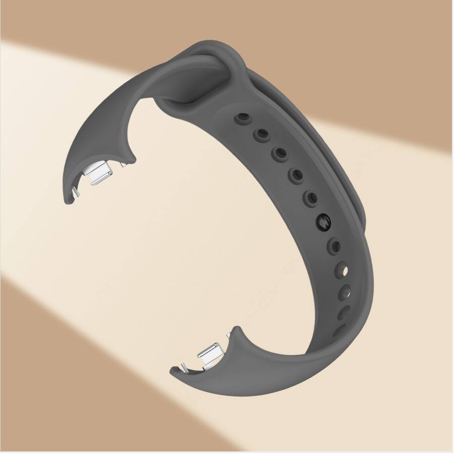Graues Silikonarmband mit Metallverbindern, offen in einer produktgestalteten Darstellung auf beigem Hintergrund.