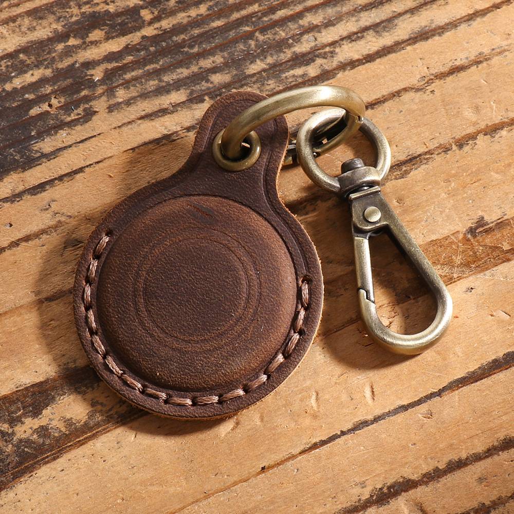 Braunes Leder-Schlüsselanhänger mit Metallschlüsselring und Clip auf einer Holzoberfläche.